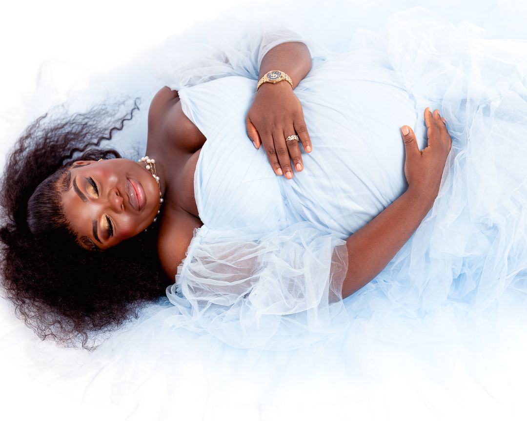 A person in white dress lying on soft white fabric with flowing dark hair.