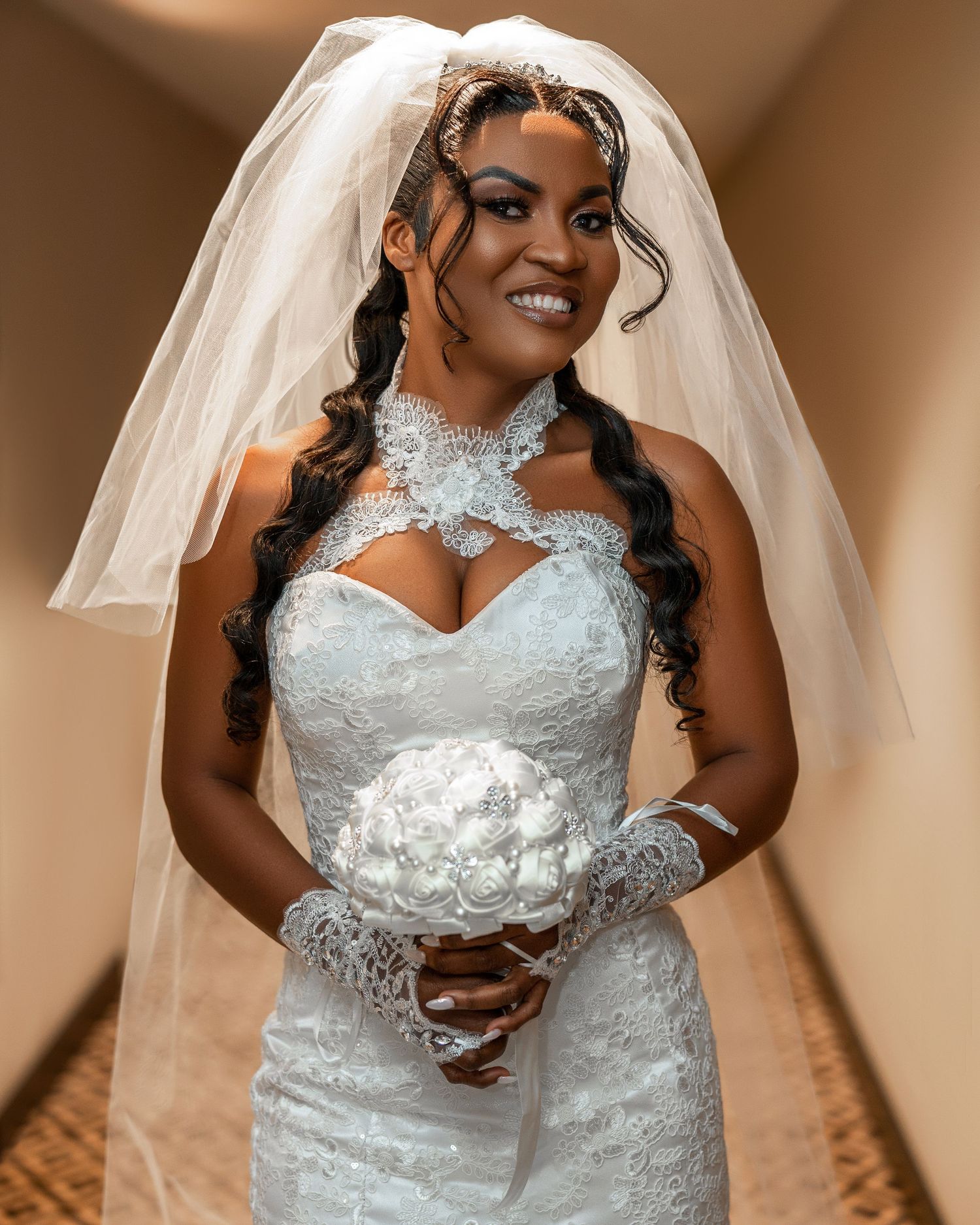Stunning bride in fitted lace wedding dress with veil and crystal headpiece smiles radiantly.