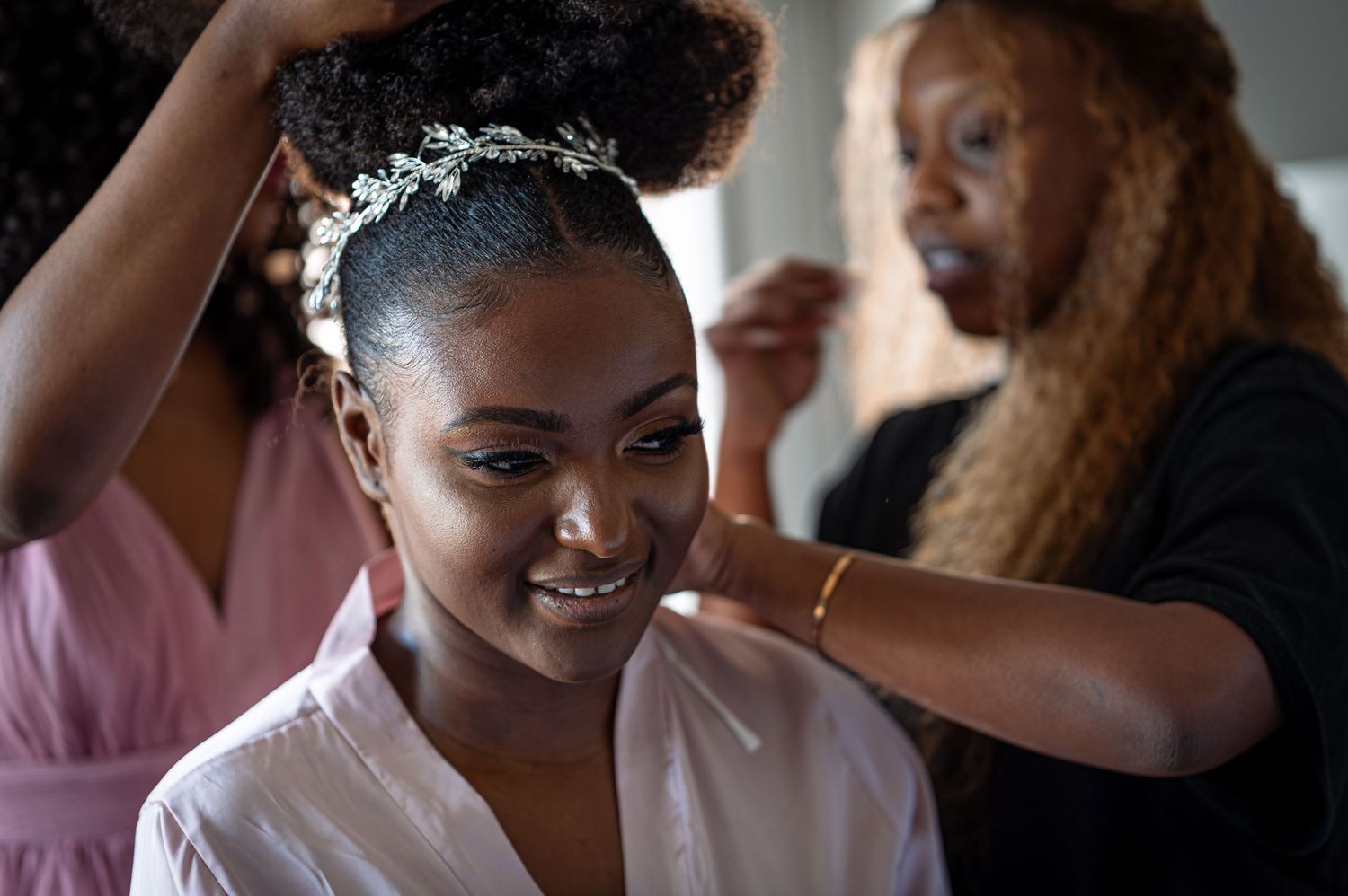 Wedding preparation scene showing hair styling moment with natural curly hair and pink robe.