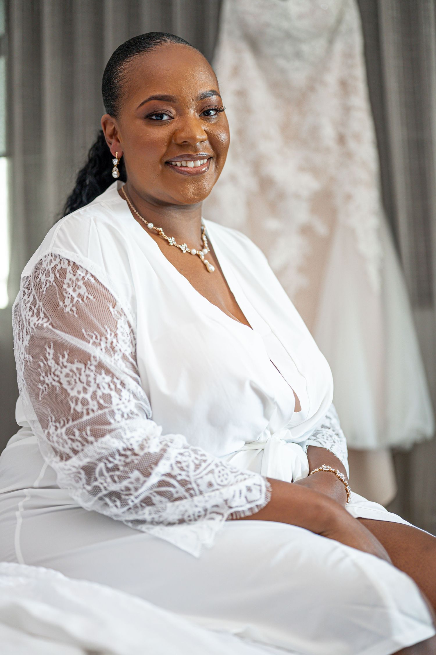 Bridal portrait showing a person in a white lace dress with long sleeves preparing for their wedding day.