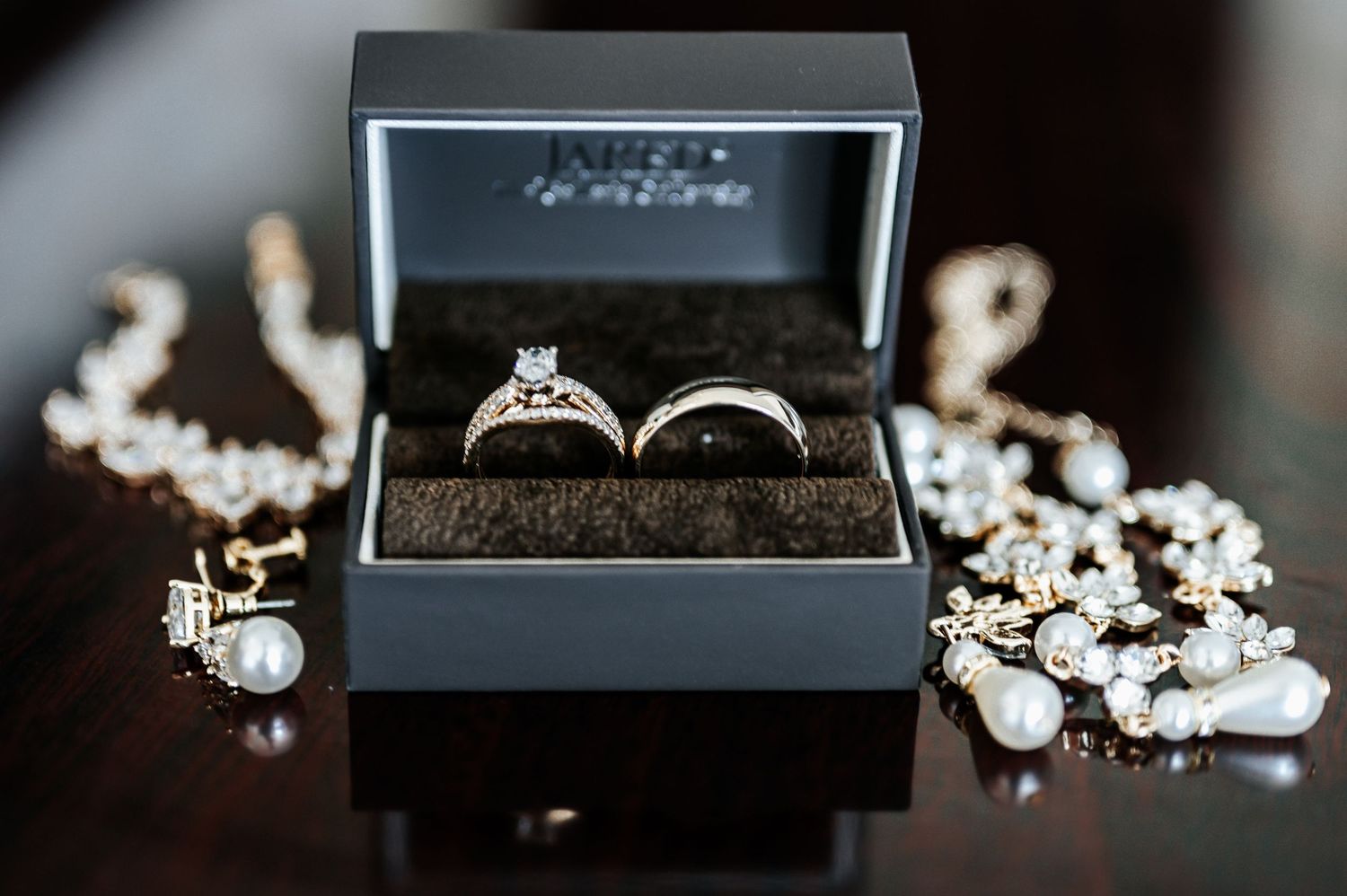 Wedding rings and pearl jewelry displayed in elegant black box.