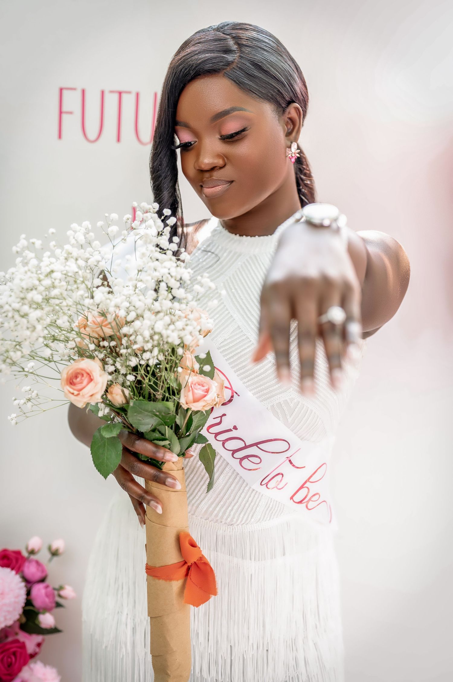 Bride in white dress shows off ring while holding delicate bouquet of roses and baby's breath.