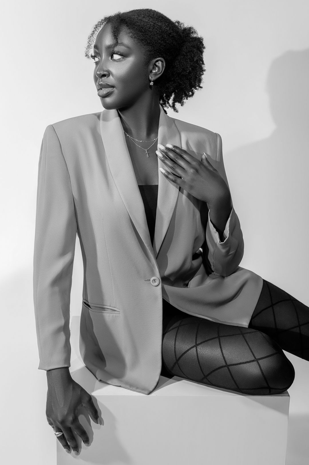 Professional studio portrait in beige blazer and patterned tights in black and white.
