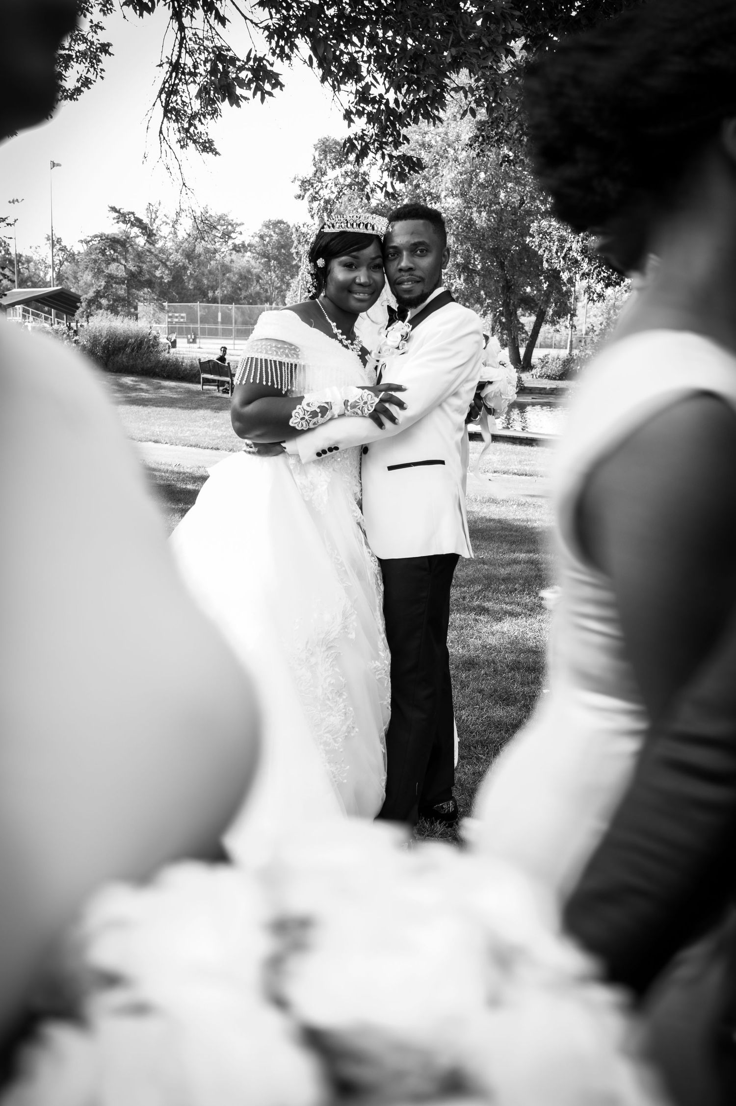 Black and white portrait of newlyweds embracing outdoors in formal attire.