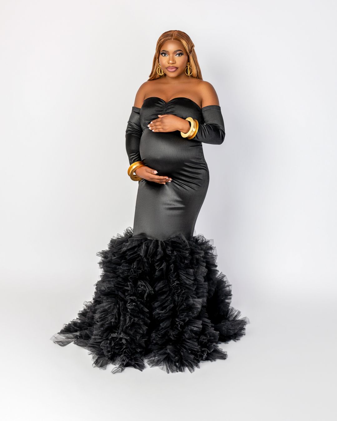 Expectant mother wearing black mermaid gown with tulle bottom for maternity portrait.