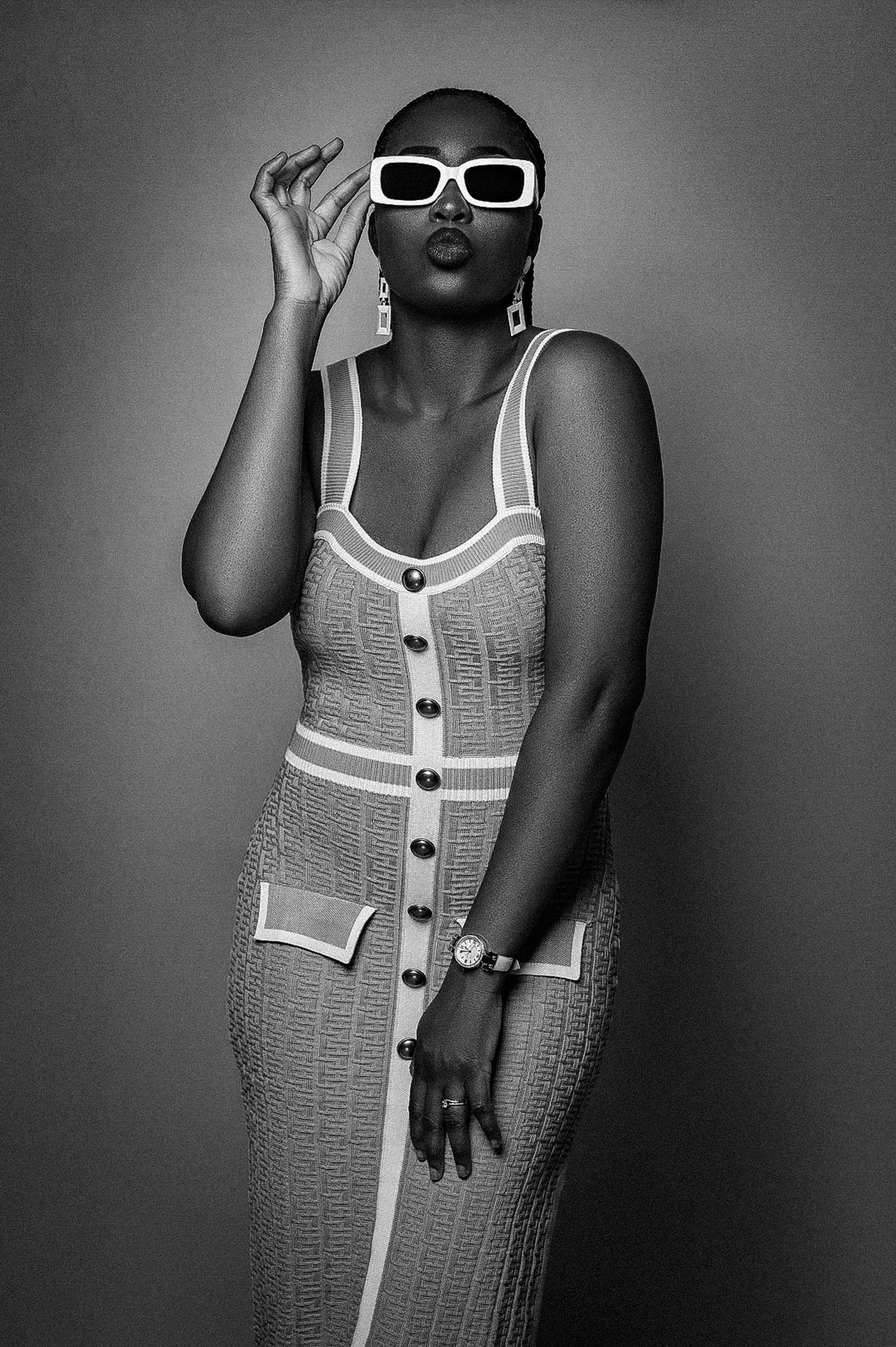 Black and white fashion portrait with model in fitted dress and retro sunglasses.