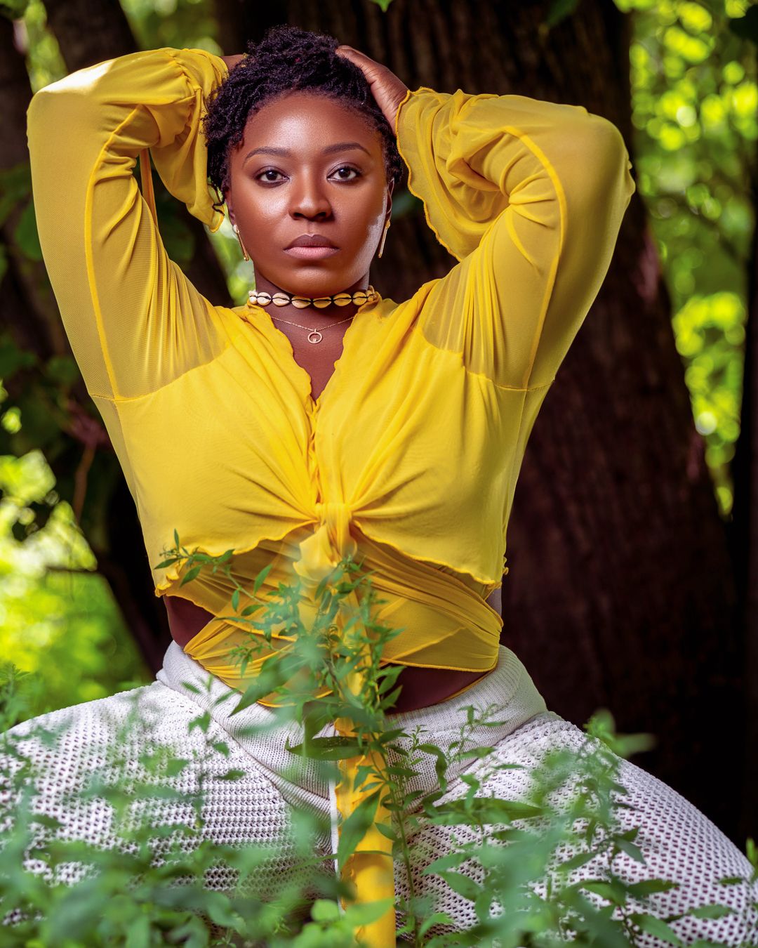 Fashion portrait in tied yellow top and white skirt against natural outdoor setting.