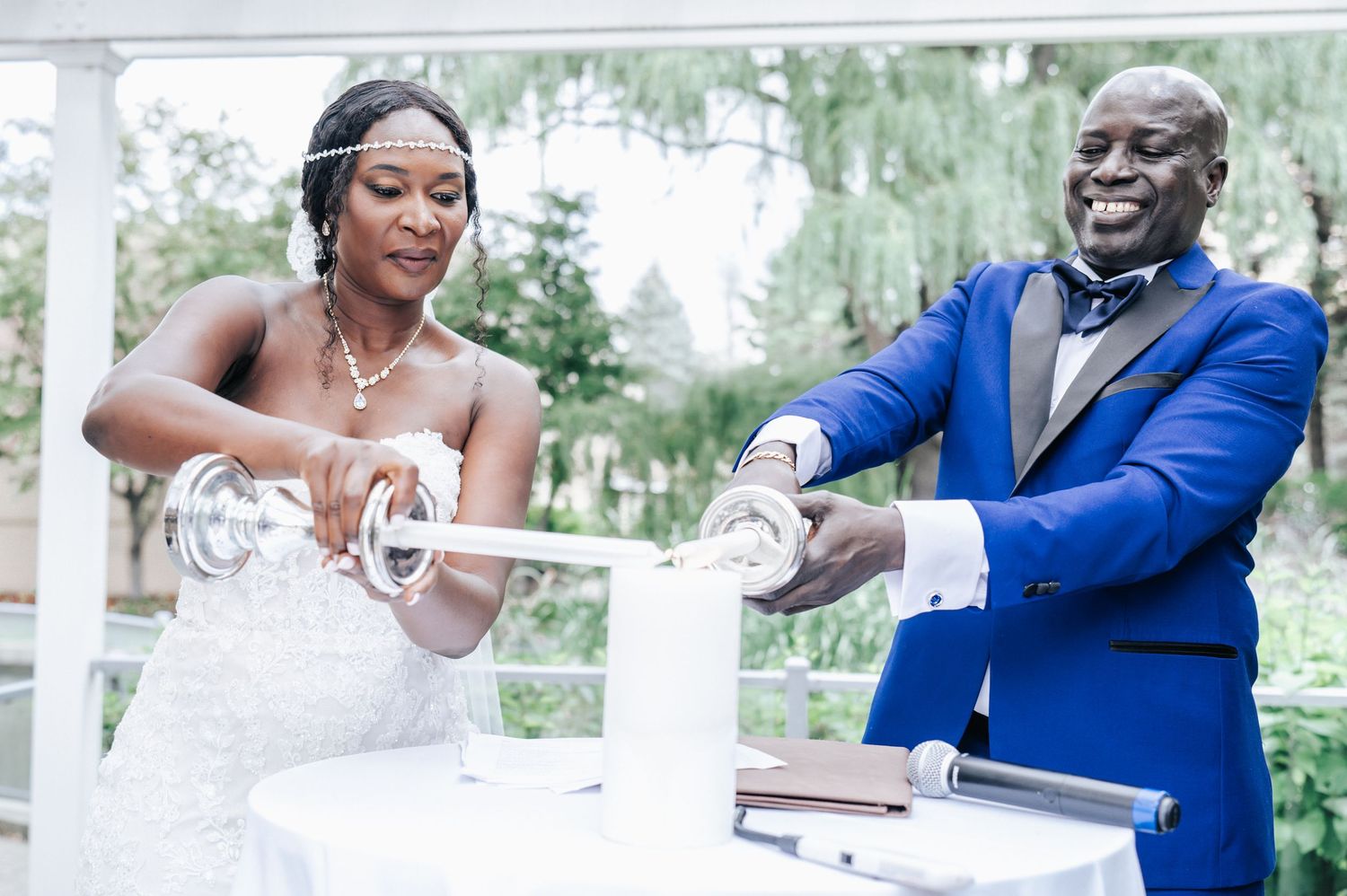 A couple participates in a unity candle ceremony during their outdoor wedding ceremony.