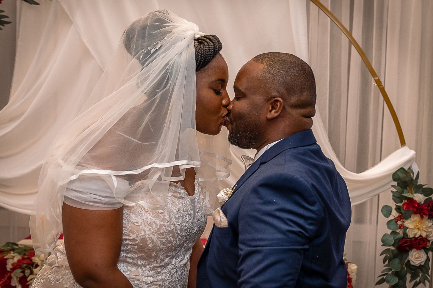A romantic moment shared between newlyweds under an elegant draped arch.