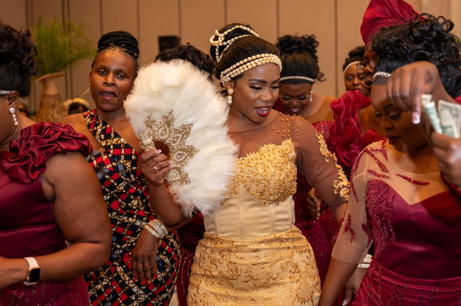 A celebration scene with a bride in a gold dress dancing among guests in colorful attire.