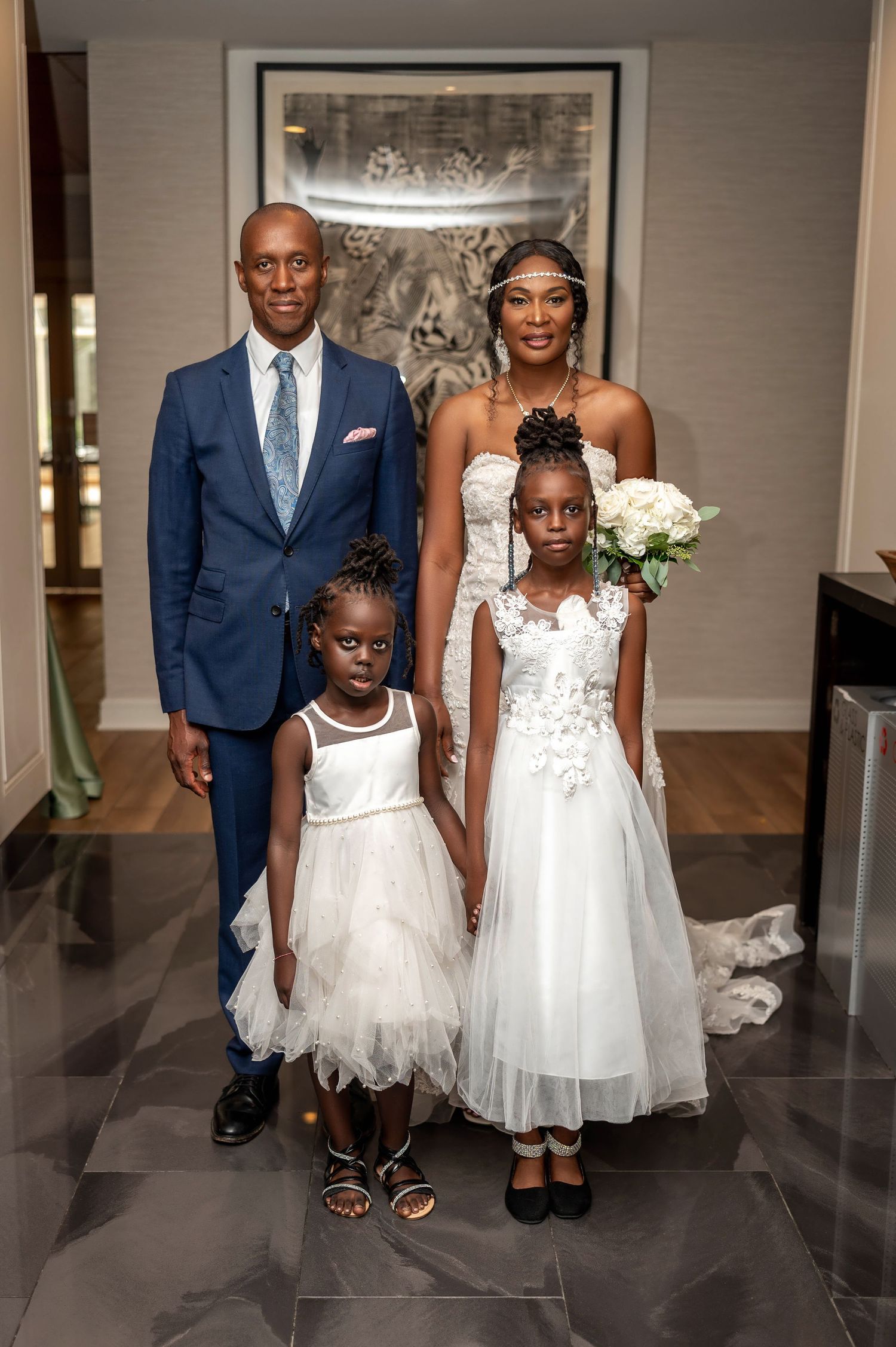 Family portrait with wedding party members in formal attire including white dresses and navy suit.