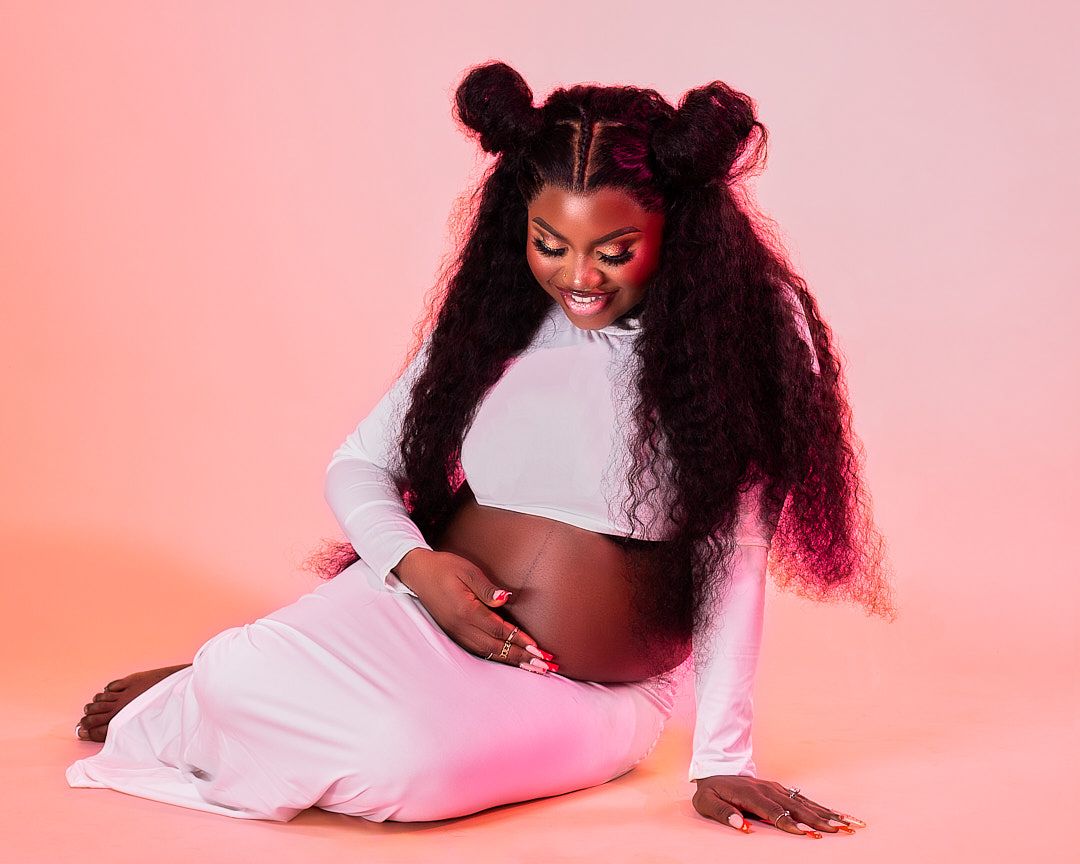 Creative maternity photos on pink background showcasing movement and style.