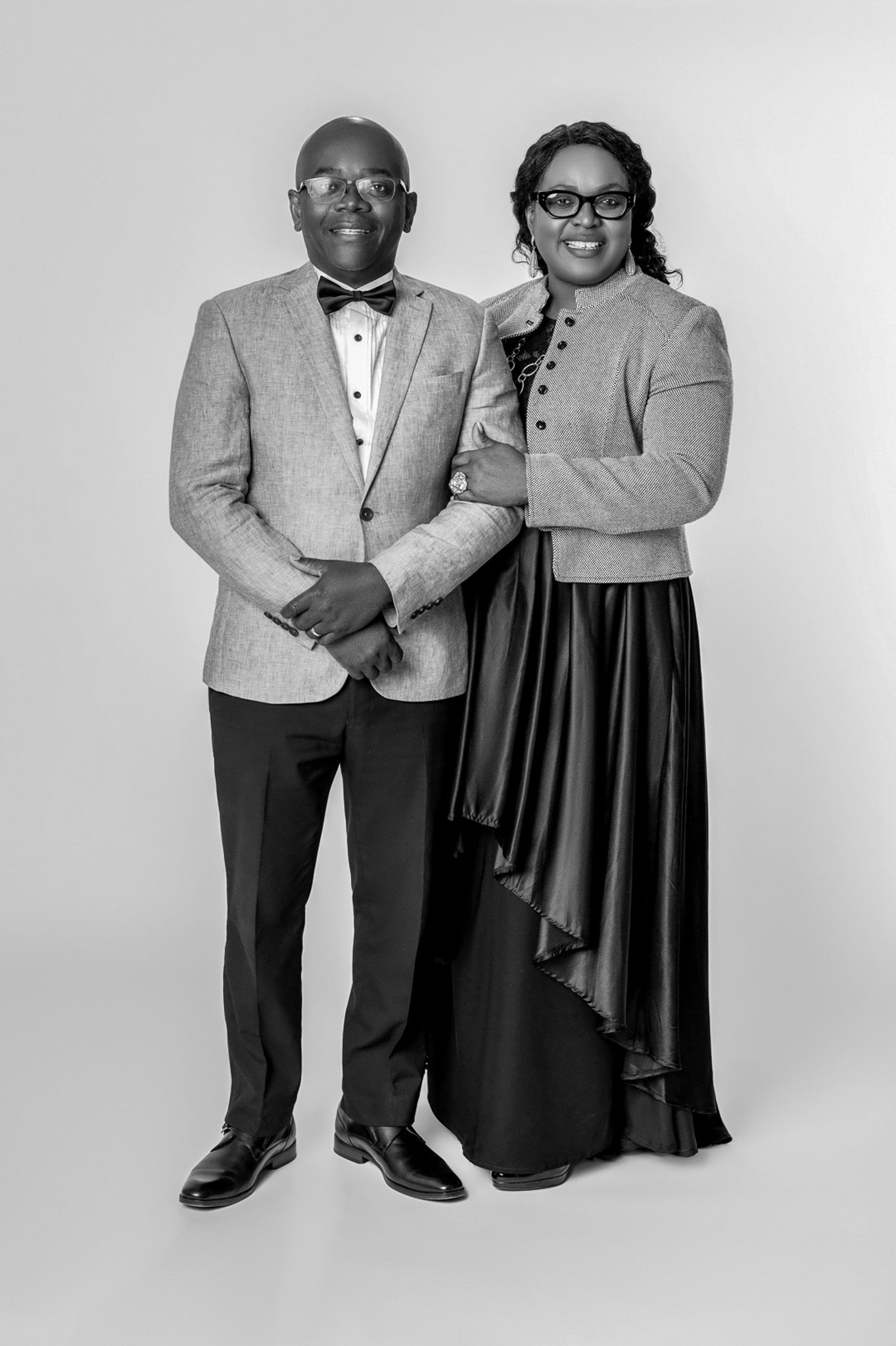 Elegant couple poses in formal attire with black bow tie and evening gown for a studio portrait.