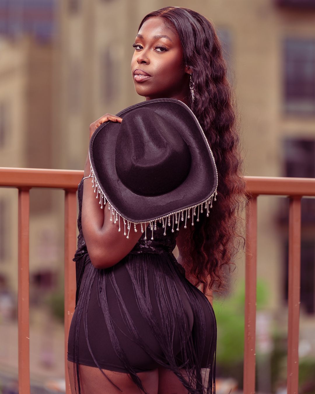 Outdoor fashion portraits featuring black hat and fringe details against urban setting.