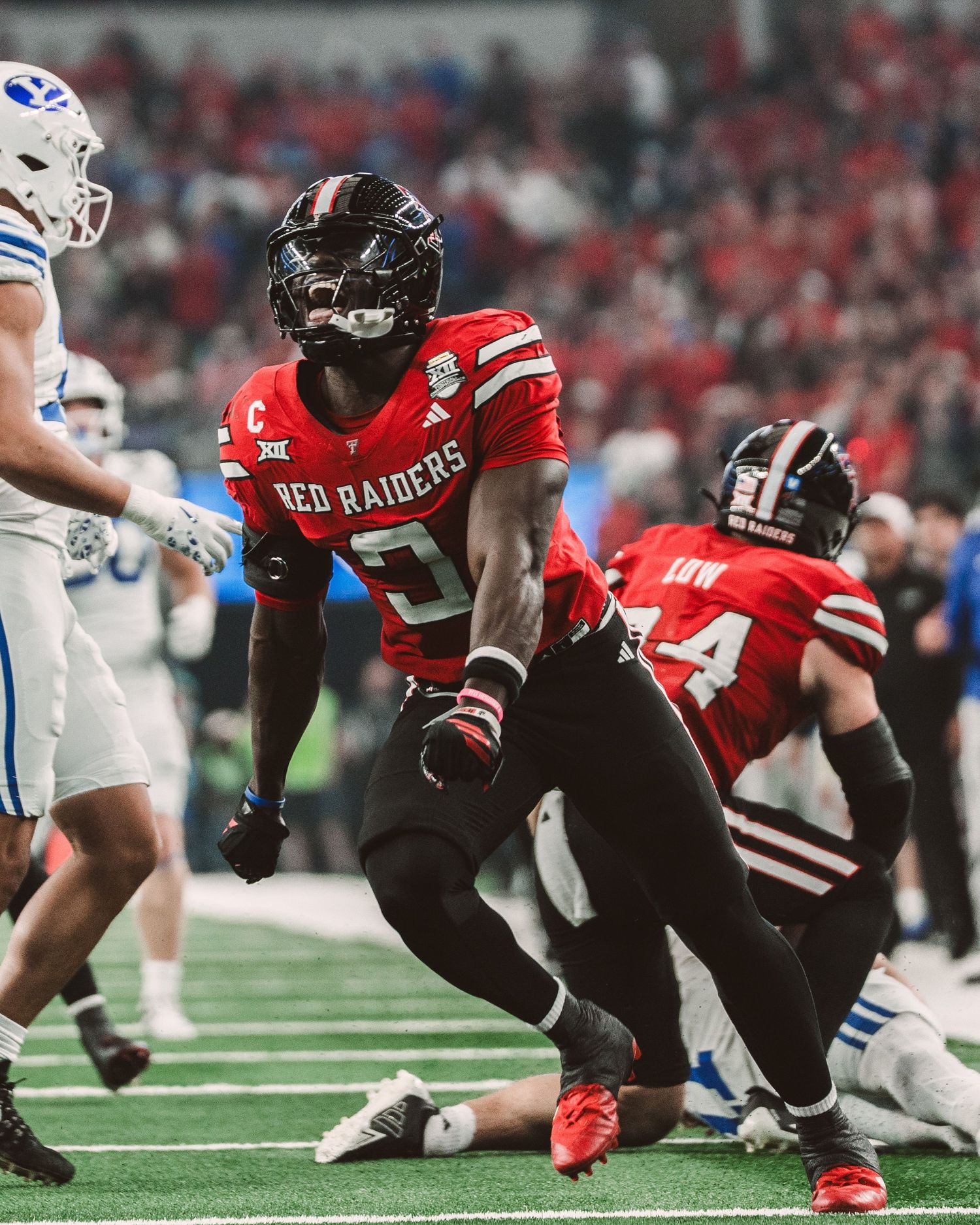 Texas Tech Red Raiders football player celebrates on field during intense college football game in red uniform.