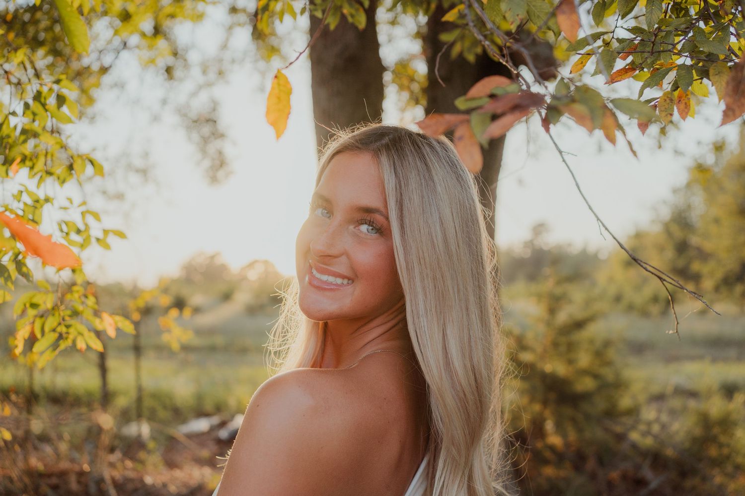 Outdoor autumn portrait session with golden sunlight filtering through yellow leaves.
