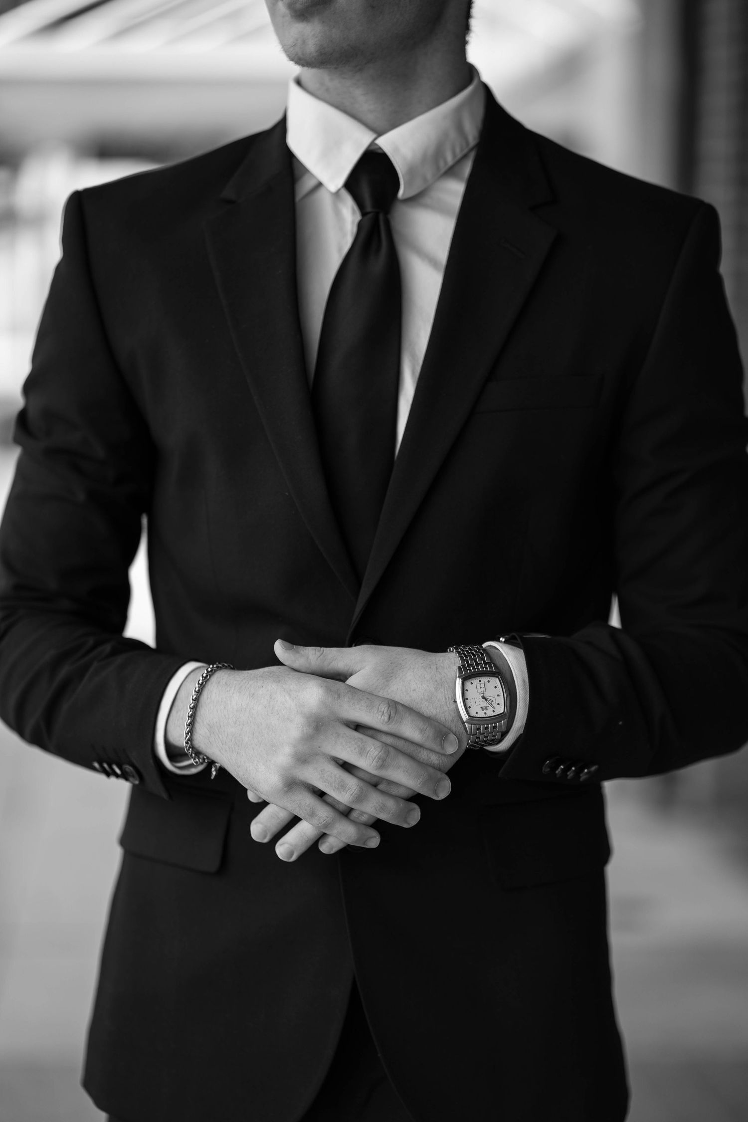 Close-up of suited professional with clasped hands showing watch and cufflinks.