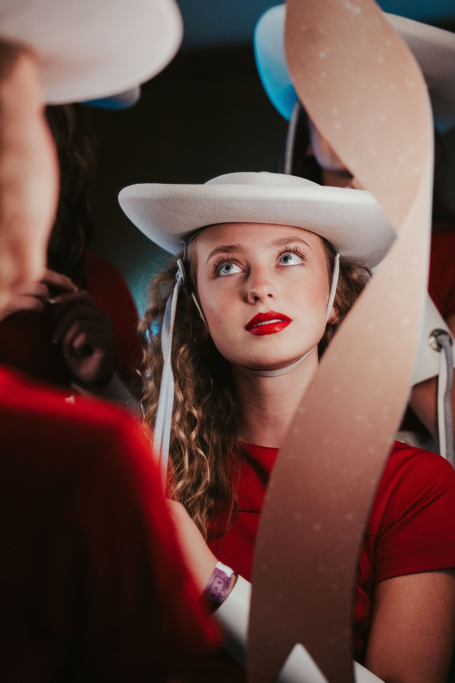 A series of artistic portraits showing someone in a white hat and red lipstick against a dramatic shadowy background.