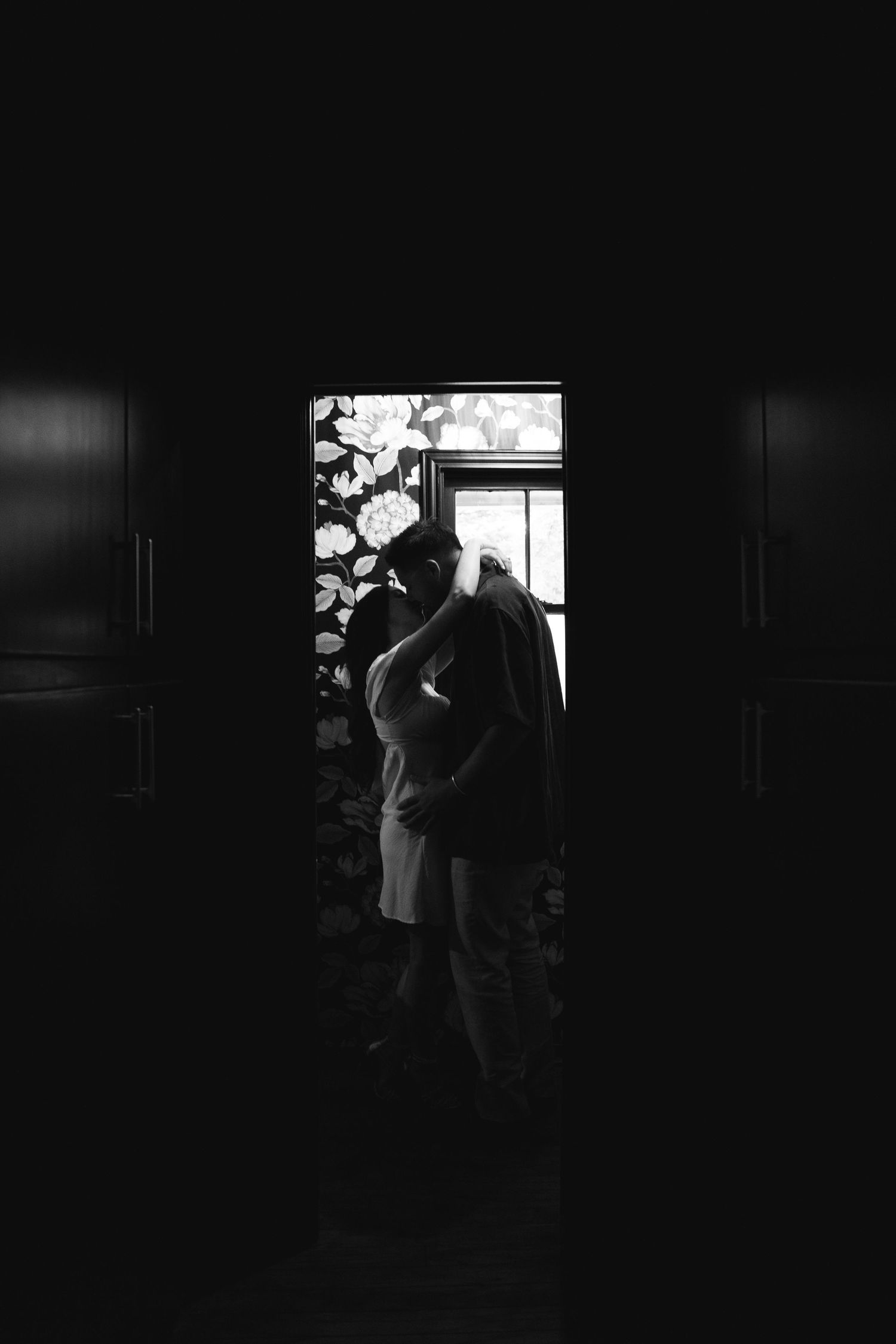 Silhouette of couple embracing in doorway with dramatic lighting and shadows.