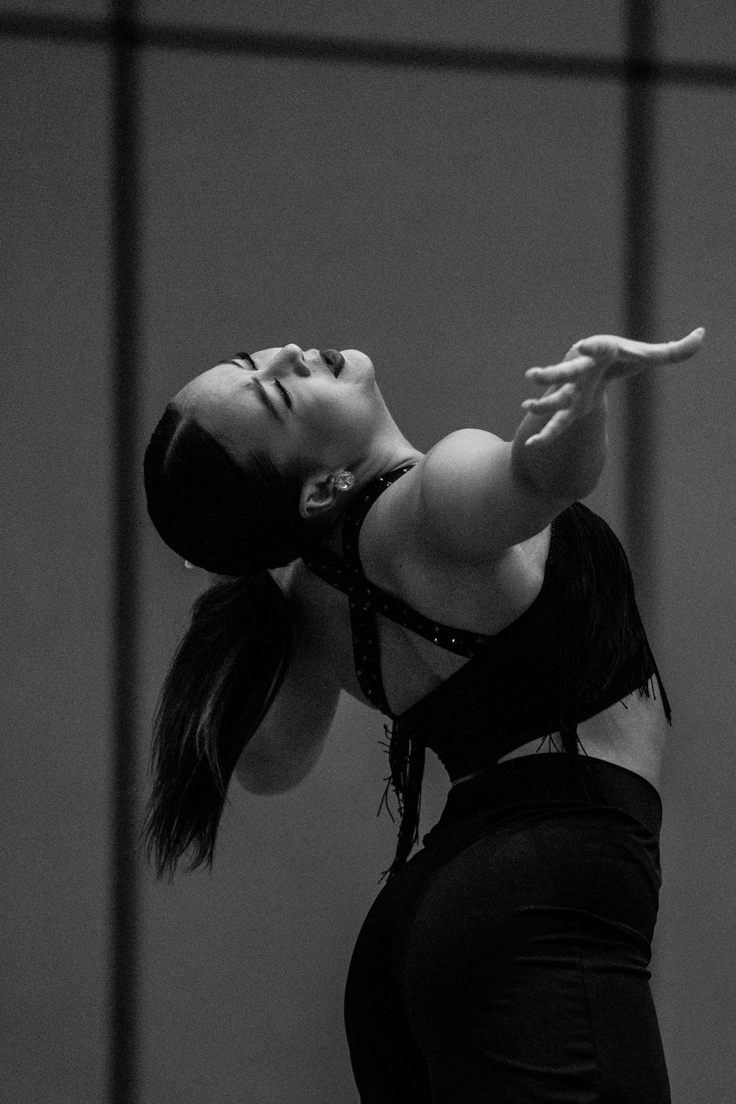 Black and white photo of a woman dancing expressively, head tilted back, arm extended gracefully in dramatic pose.