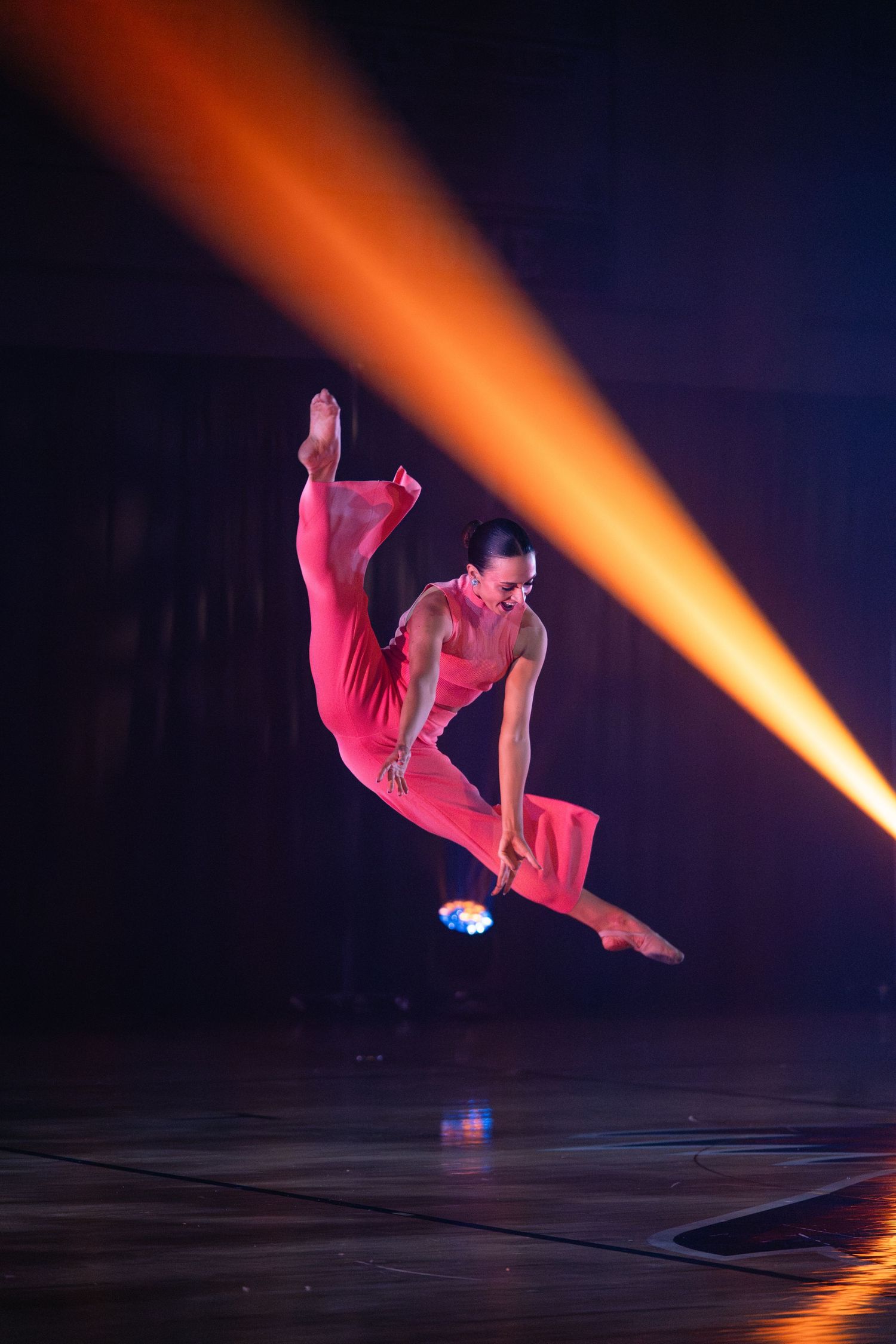 Dynamic dance performance sequence with orange lighting showing a performer executing an aerial movement.
