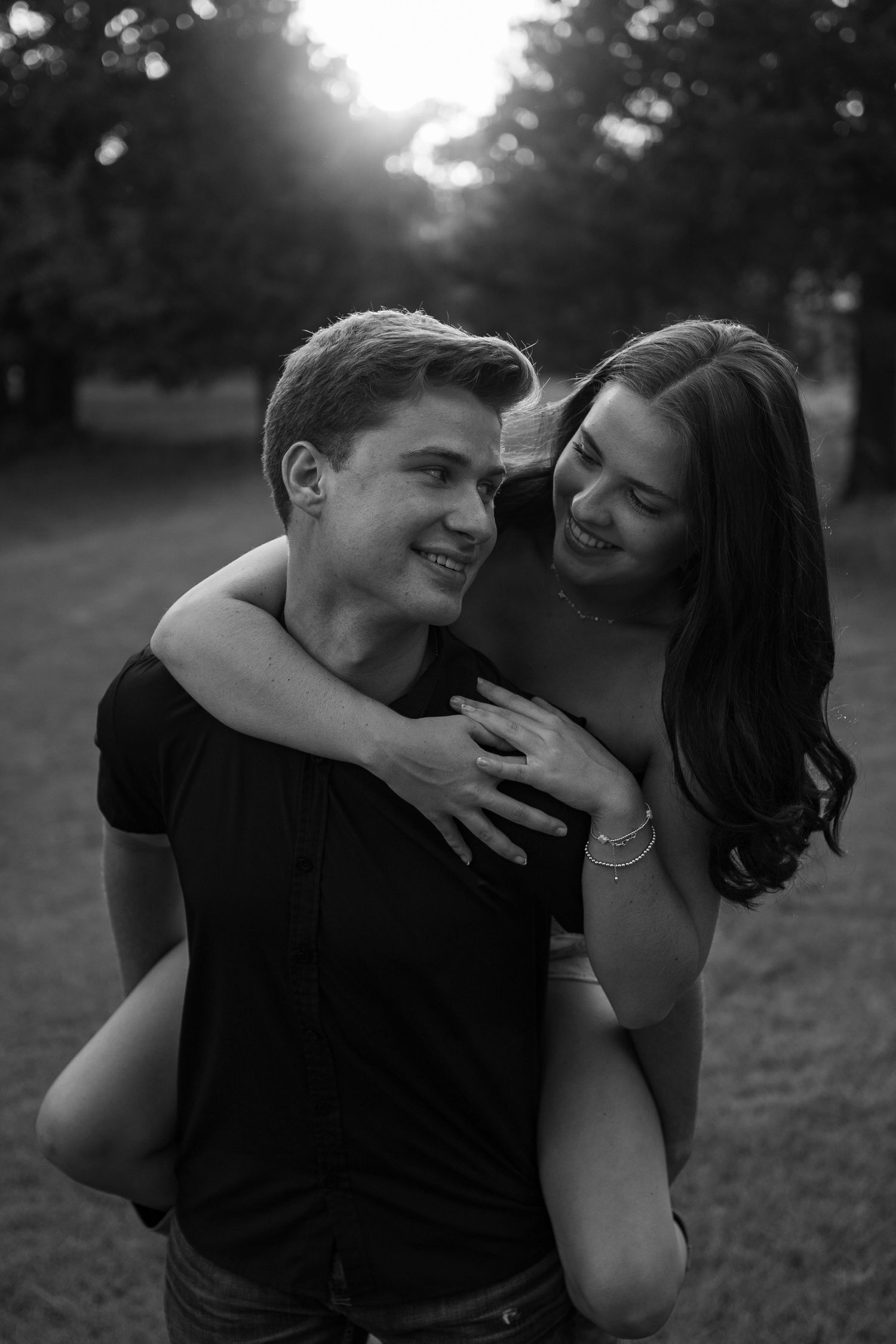 Playful piggyback ride moment captured in black and white during sunset.