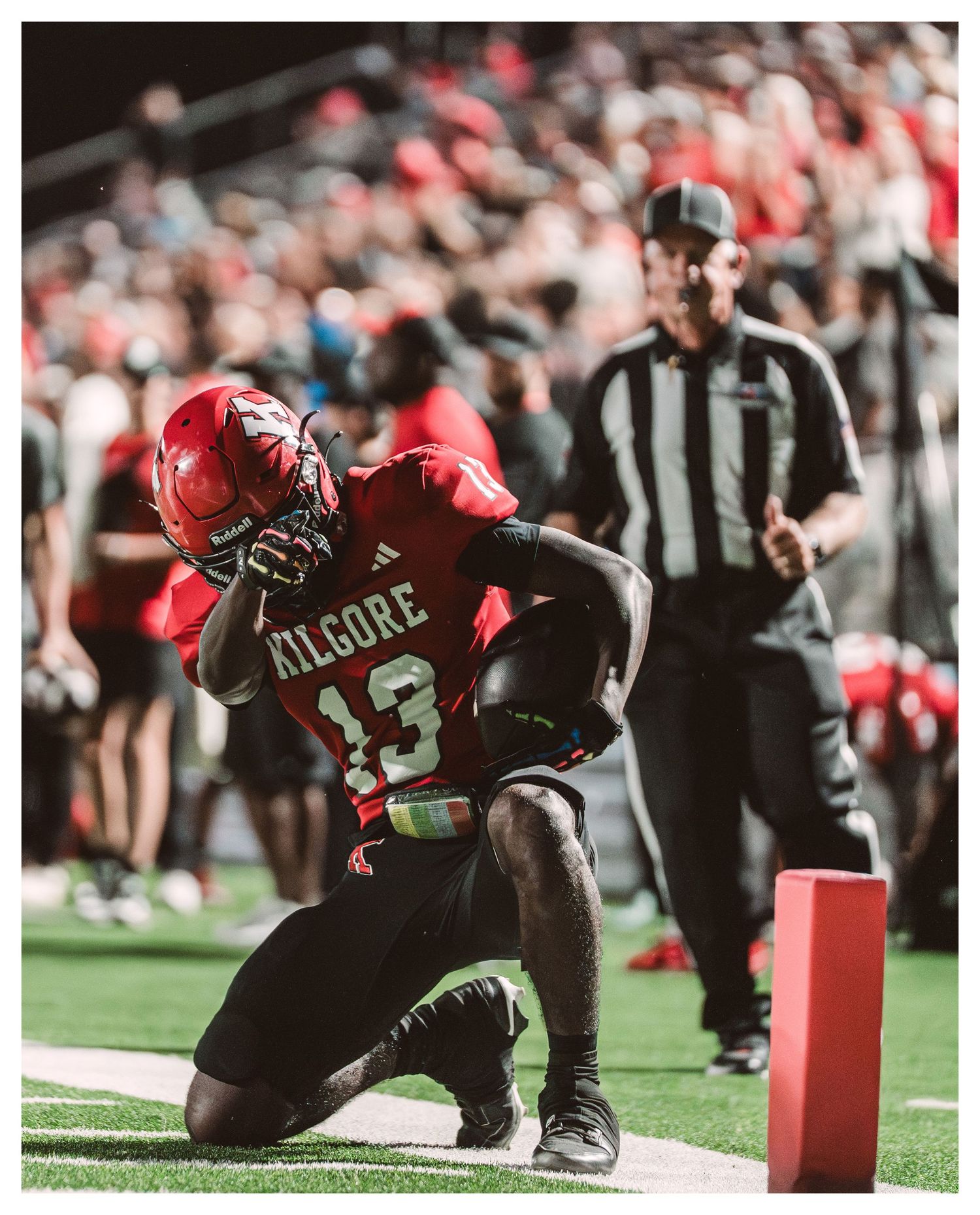 Football player #13 Kilgore kneels in the end zone after a touchdown, with a referee visible in the background.
