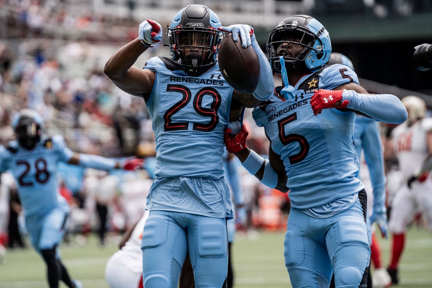 Football players celebrate in light blue uniforms during game.
