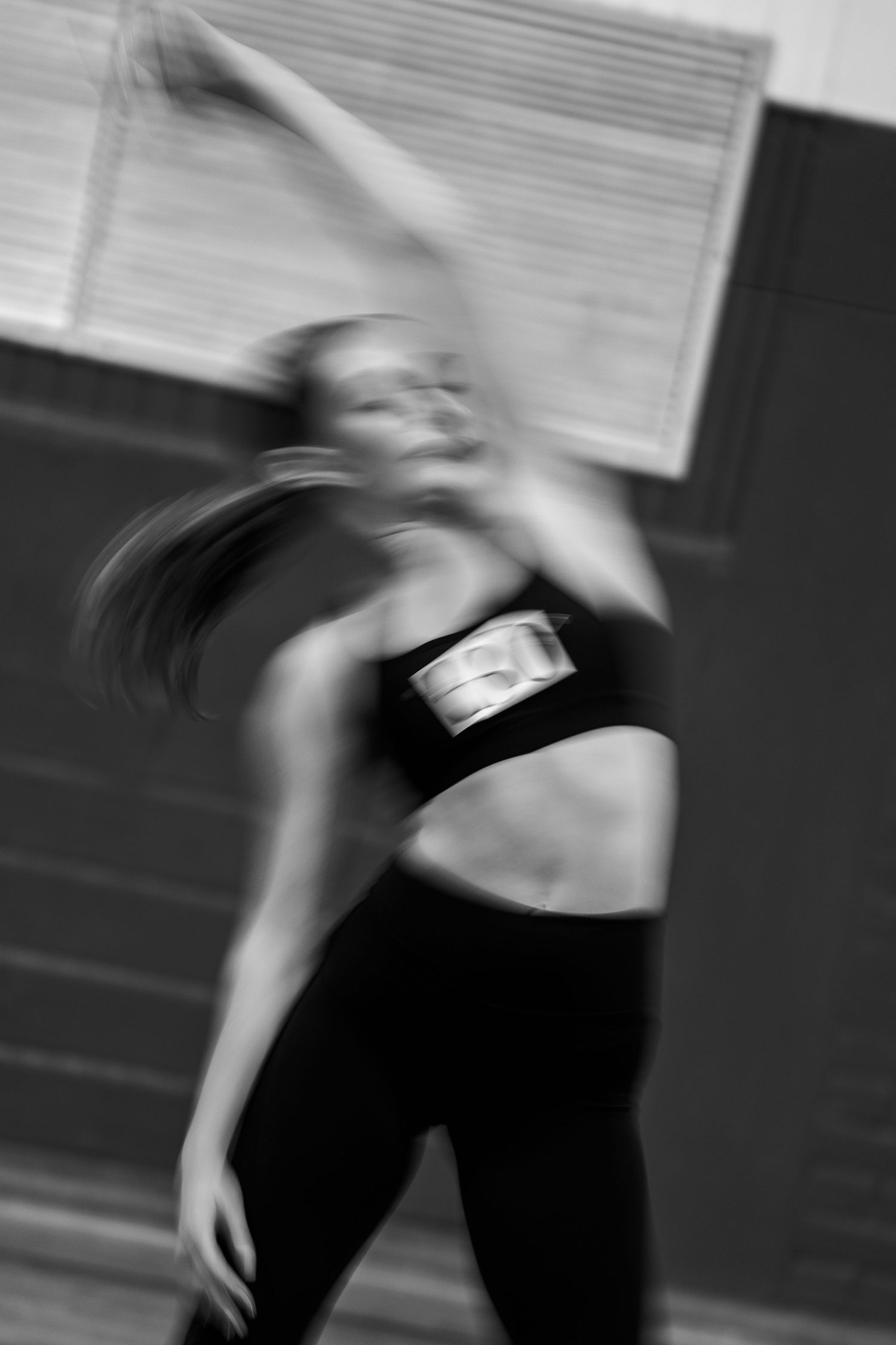 Black and white motion blur photo of a female dancer performing an expressive contemporary dance routine in a studio.