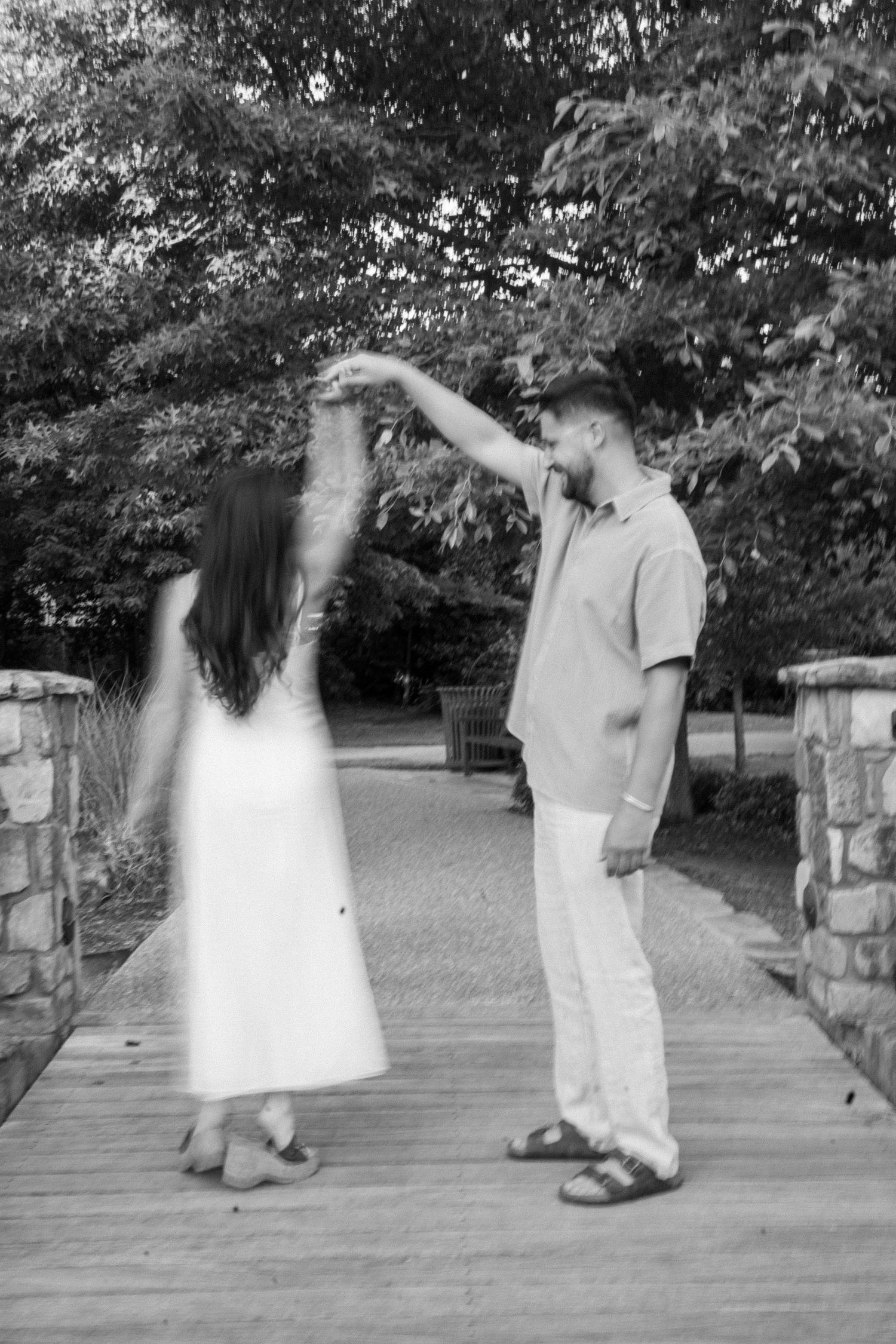 Couple dancing on stone bridge pathway in black and white photography.