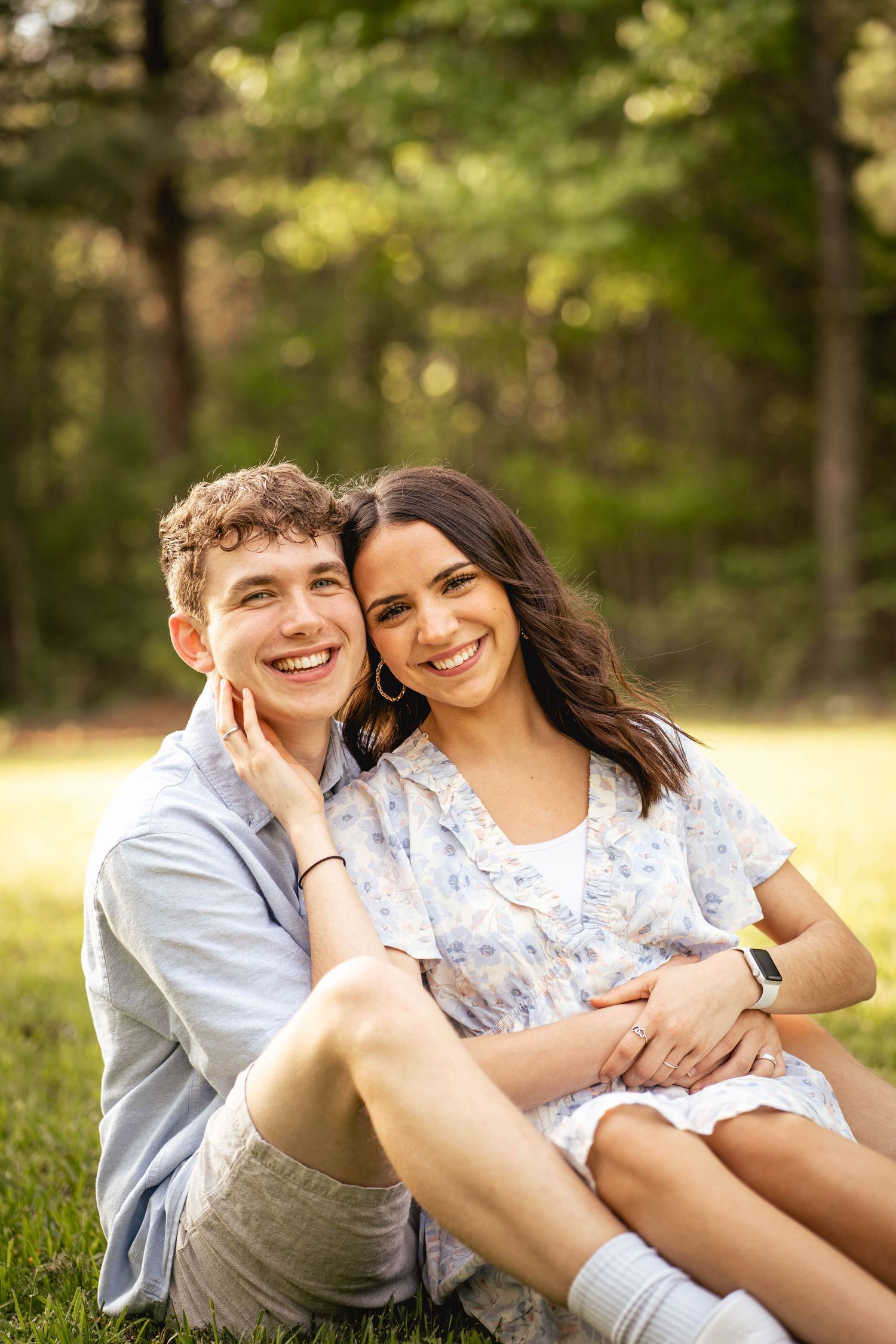 Couple relaxing together on grass during golden hour outdoor photo session.