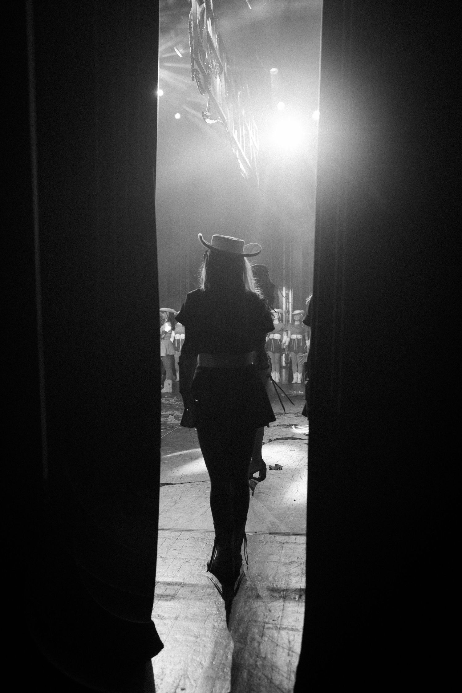 Silhouette of a performer walking through backstage doors with dramatic lighting.