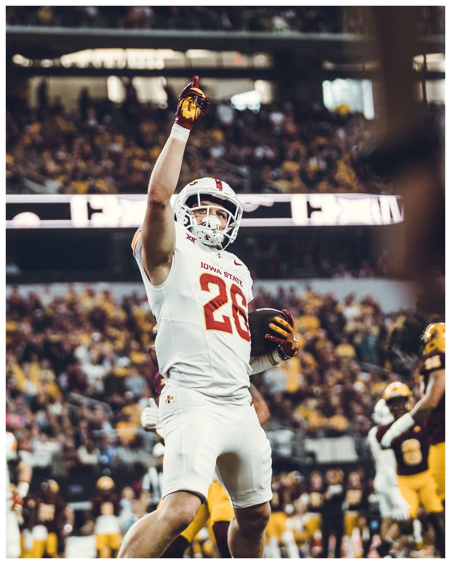 Football players in white jerseys make a defensive play during a stadium game.