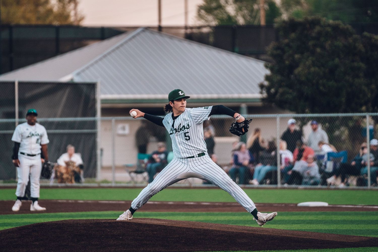 Baseball pitchers practicing their throwing form on a green athletic field.