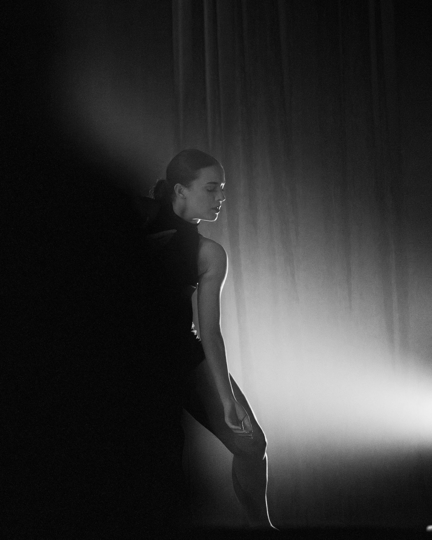 Artistic silhouette of a performer against dramatic side lighting.