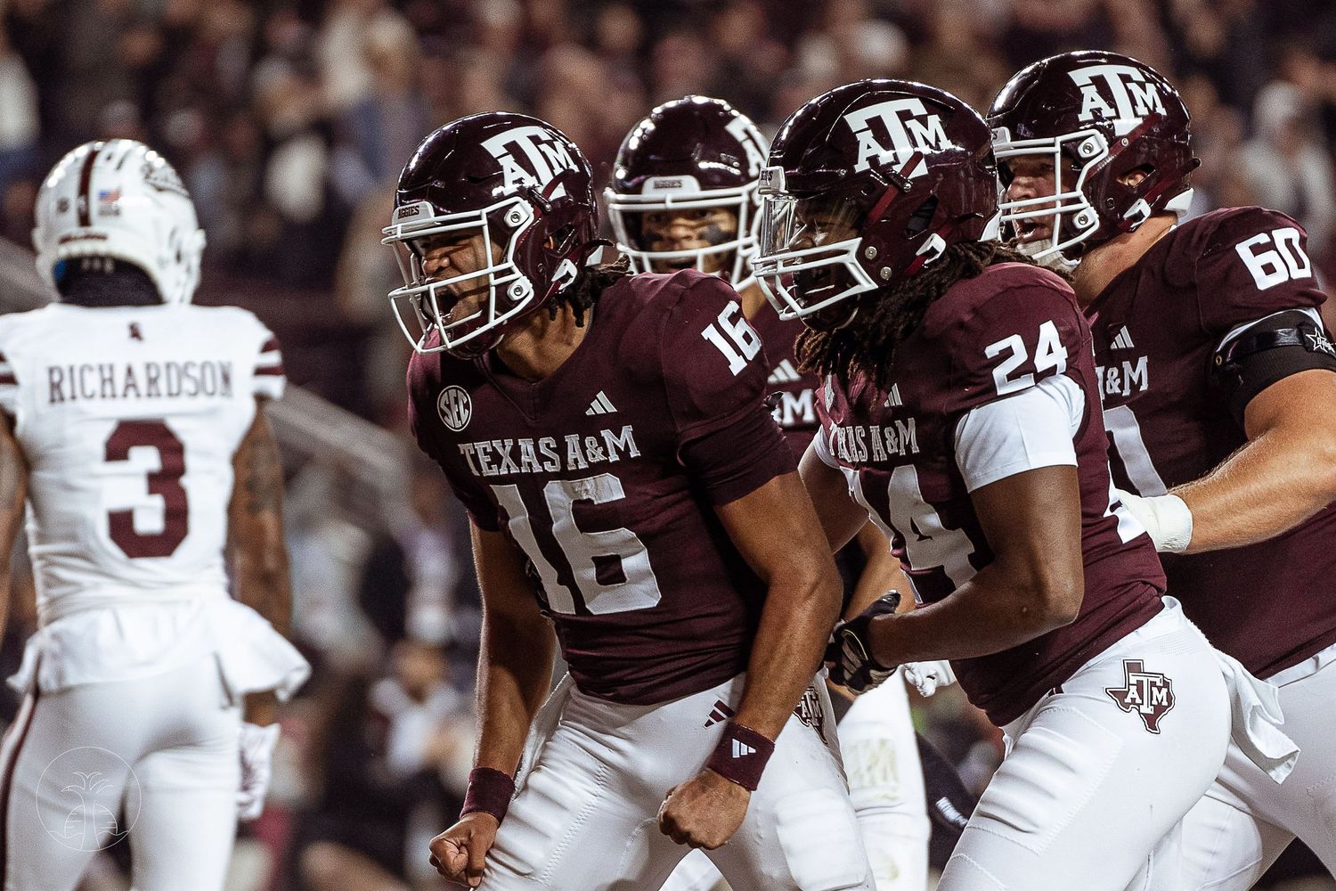 Texas A&M Aggies football players celebrate on the field during a night game at Kyle Field.