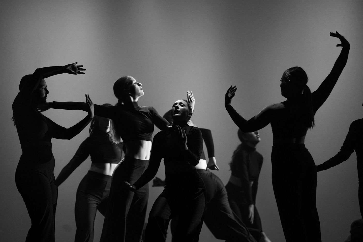 Silhouetted dancers strike expressive poses in artistic group performance.