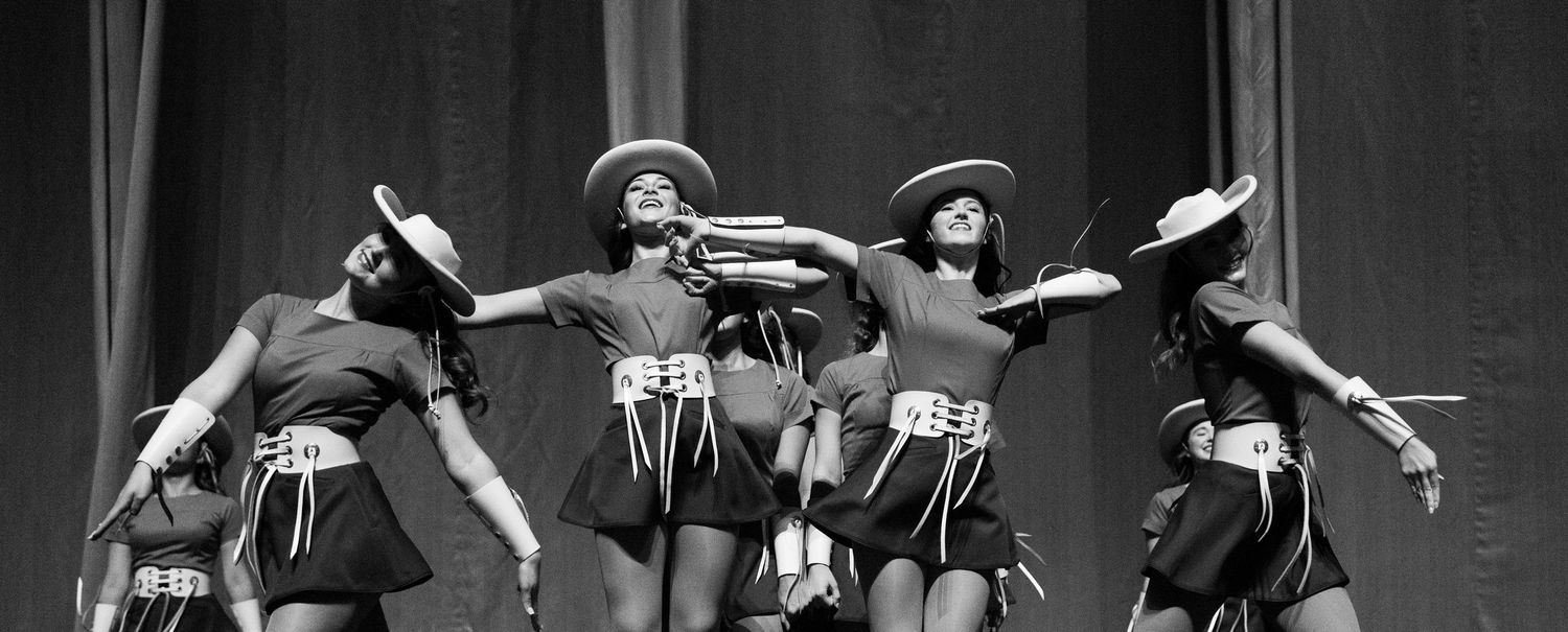 Vintage black and white photo showing musicians performing on stage with instruments and dramatic lighting.