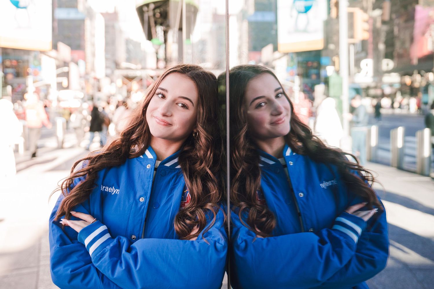 Two people in matching bright blue hoodies pose playfully together outdoors on a sunny day.