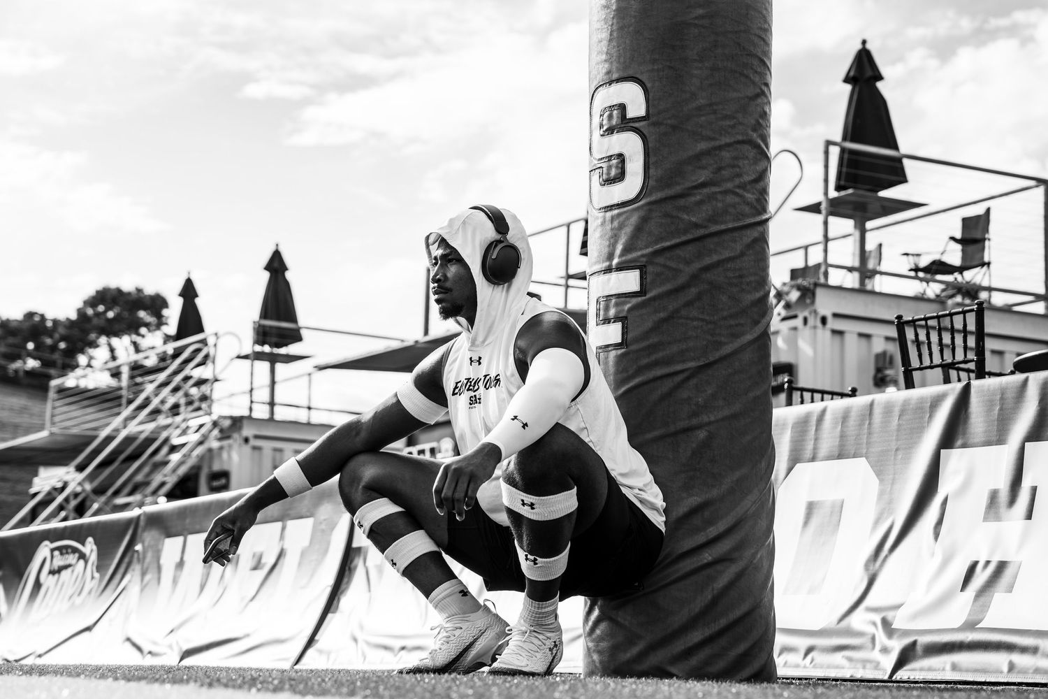 A soccer goalkeeper in uniform crouches in position by the goalpost during a match in black and white photography.