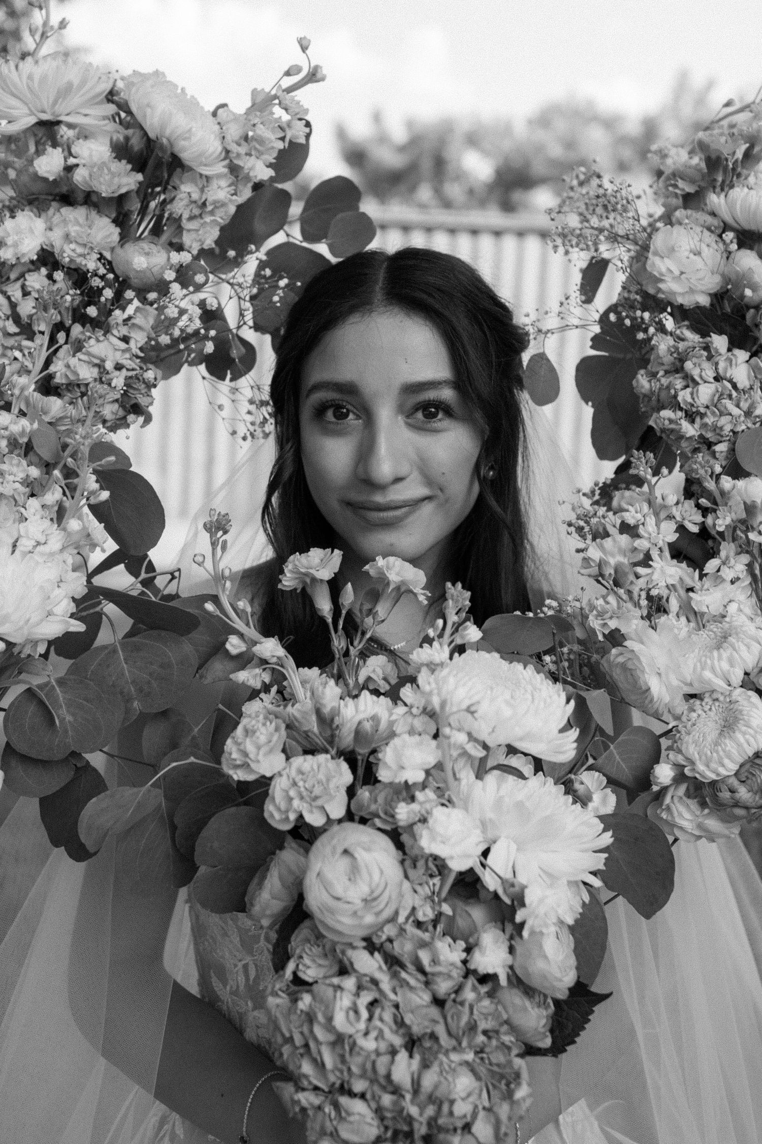Bridal portrait with luxurious floral bouquet featuring roses and mixed flowers in black and white.