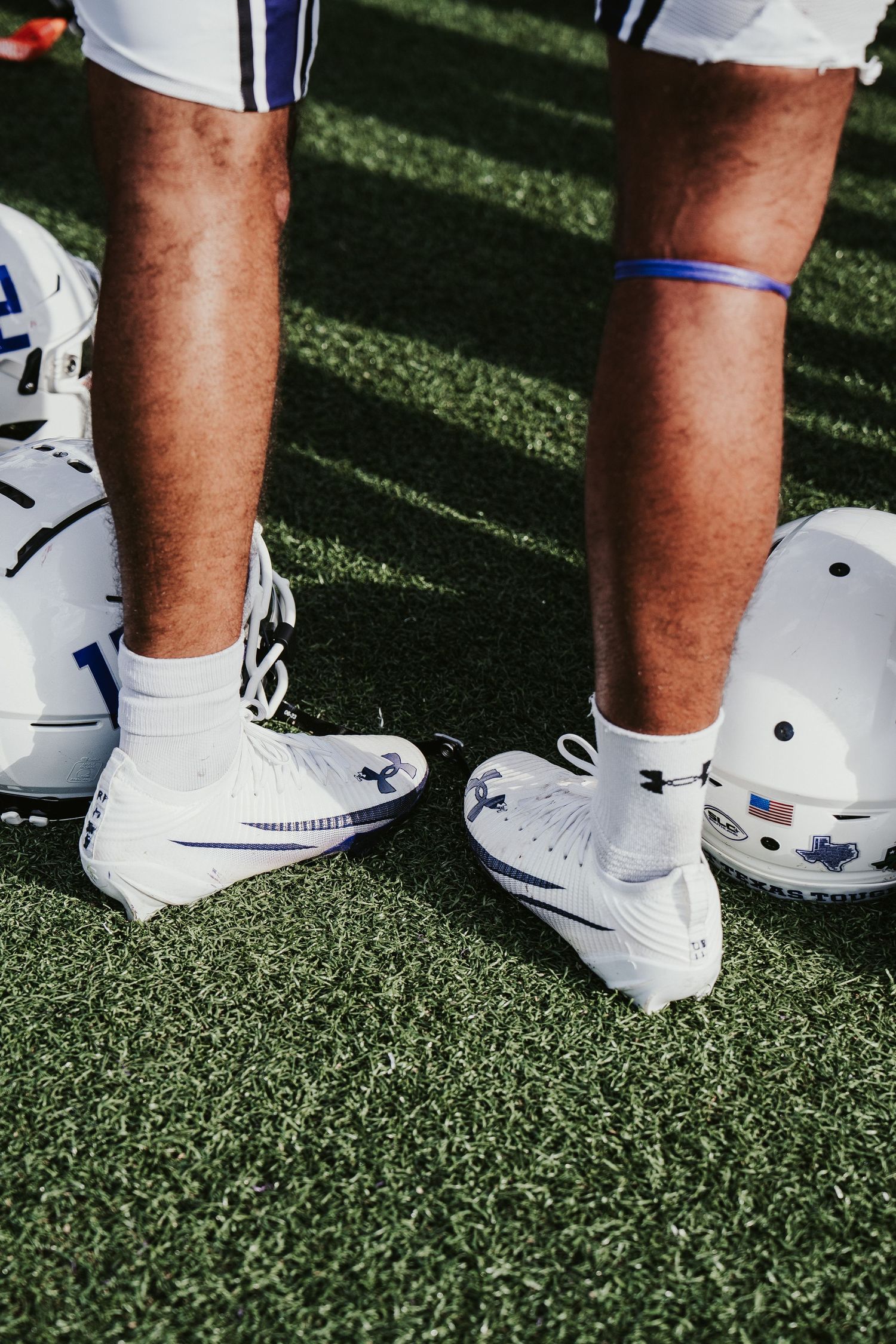 Close-up view of white athletic shoes on artificial turf with blue and black accents.