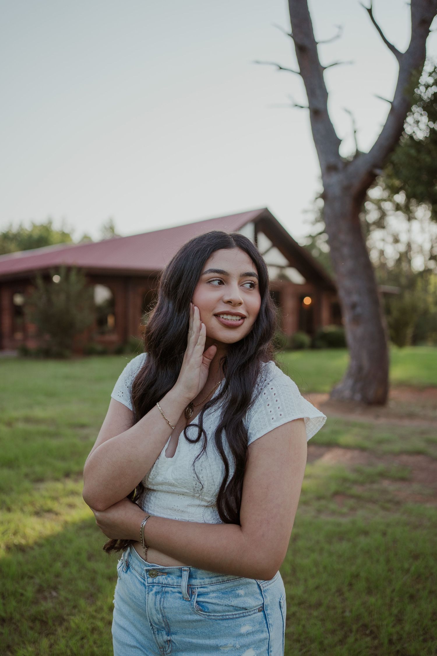 Candid outdoor portrait at sunset with rustic cabin in background.