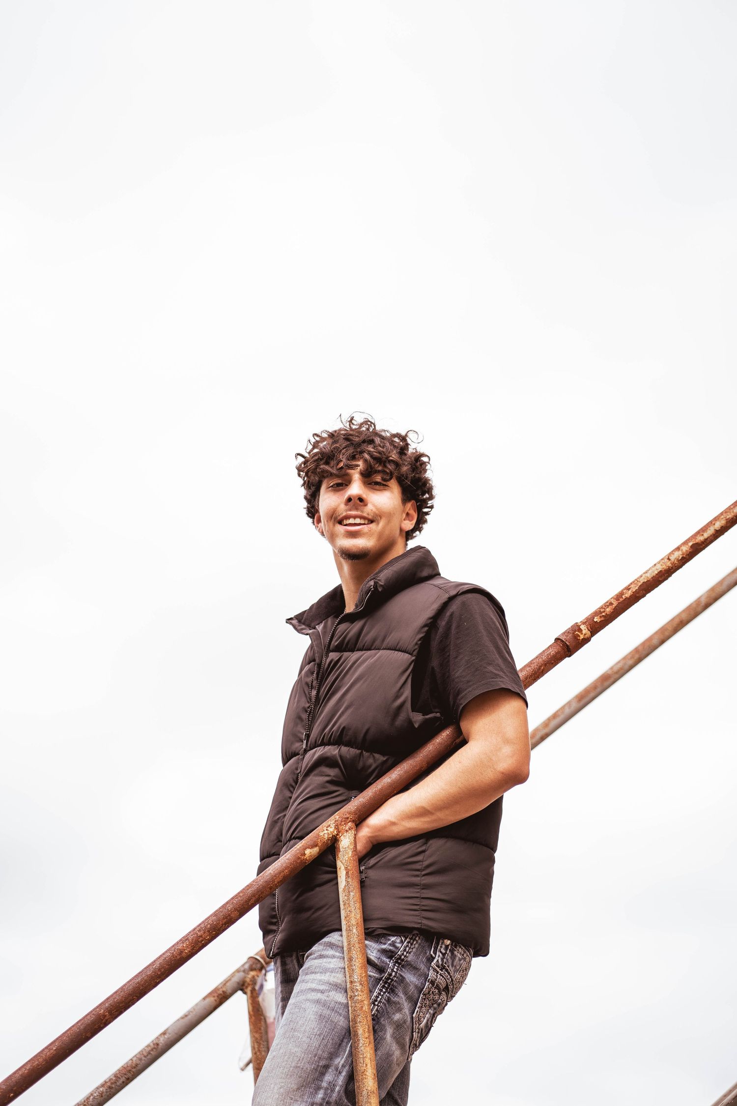 Person in dark clothing climbing on wooden beams against white background.