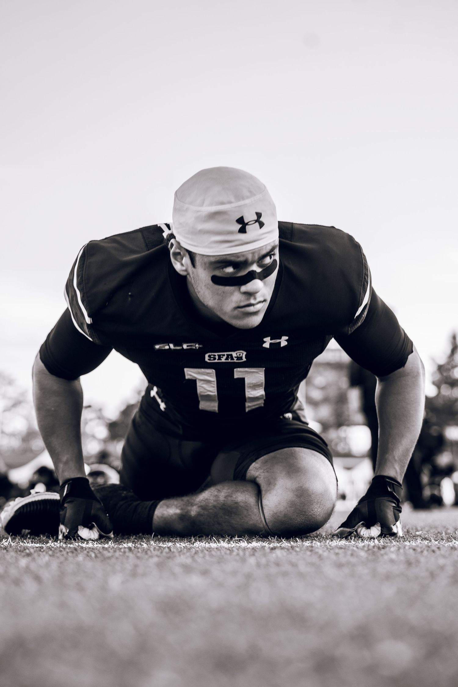 Black and white photo sequence showing an athlete doing push-ups on grass while wearing Under Armour gear.