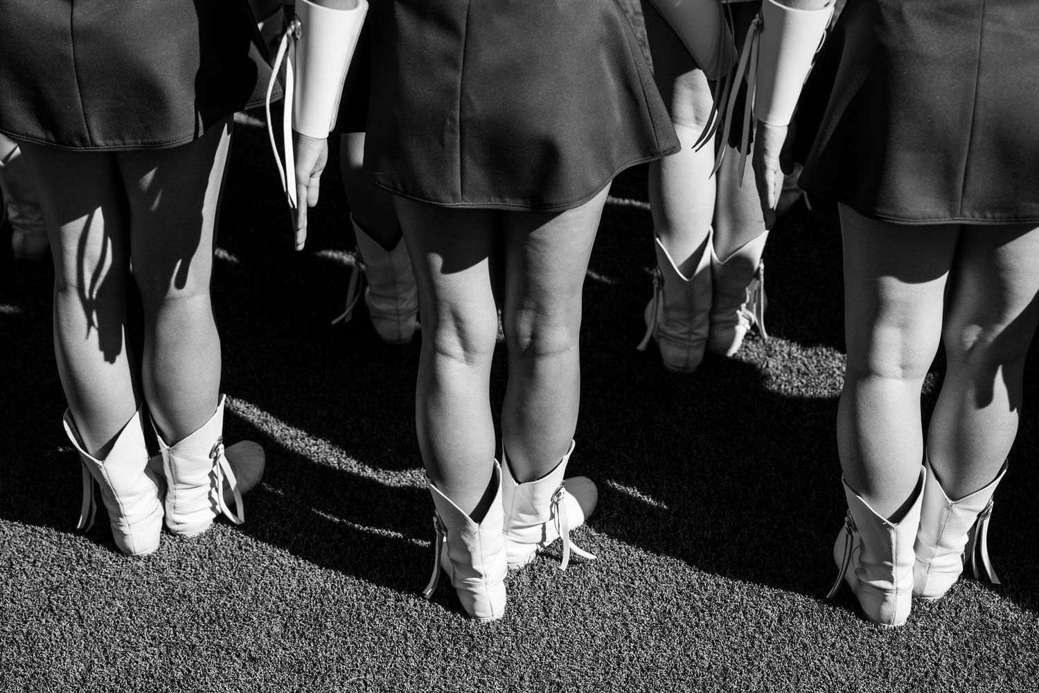 A line of people showing off their shoes and feet in a black and white photograph.