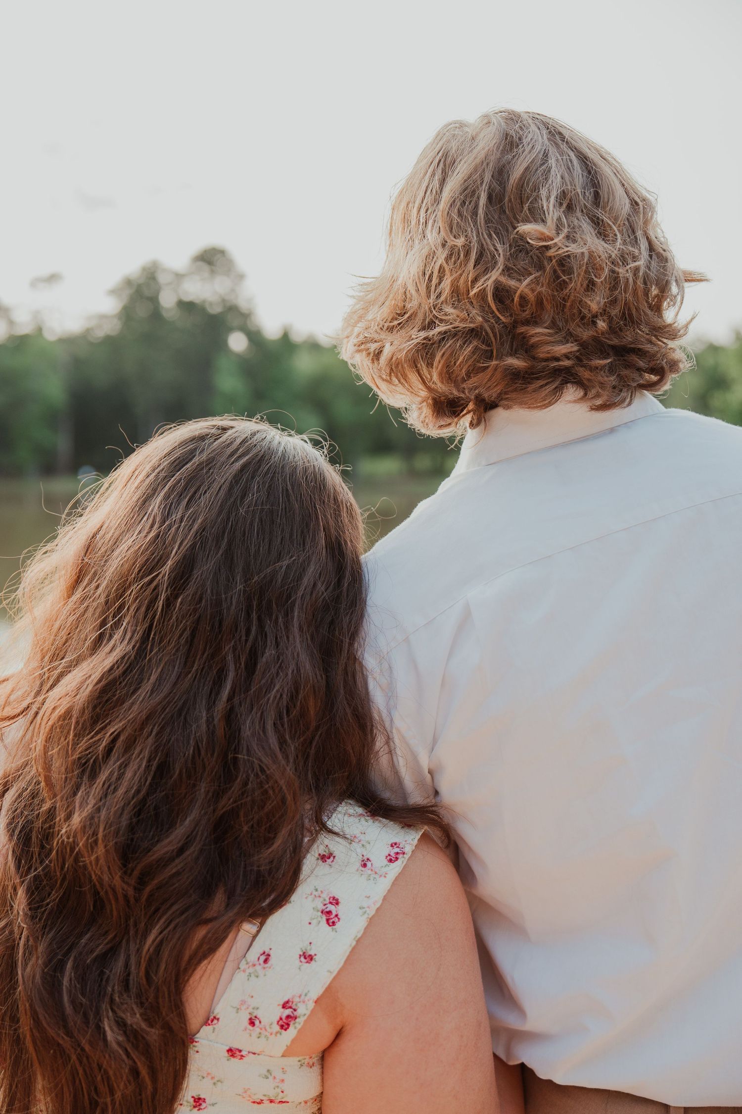 Close-up of couple from behind overlooking nature scene at golden hour.
