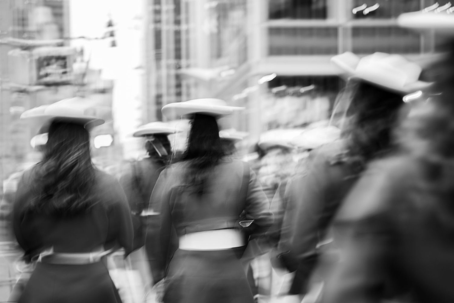 A black and white motion-blurred photograph shows a crowd of people walking on a busy city street.