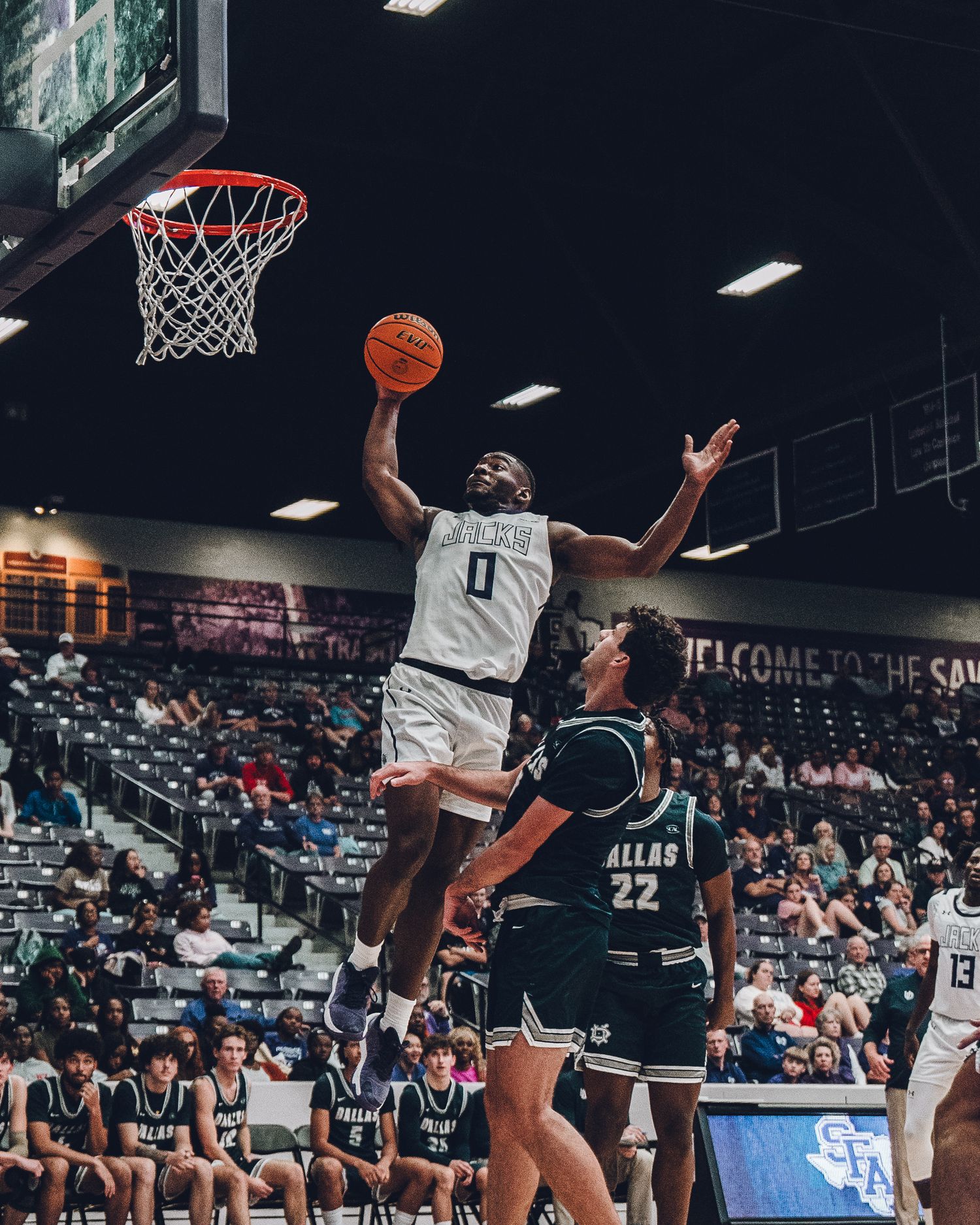 Basketball player drives to the hoop for a layup during an intense game against defender wearing number 22.