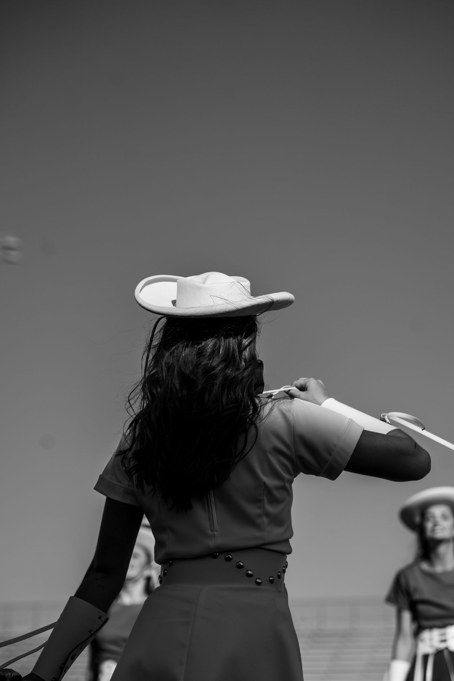 Black and white photo showing a woman in dance attire and cowboy hat performing on stage during a performance.